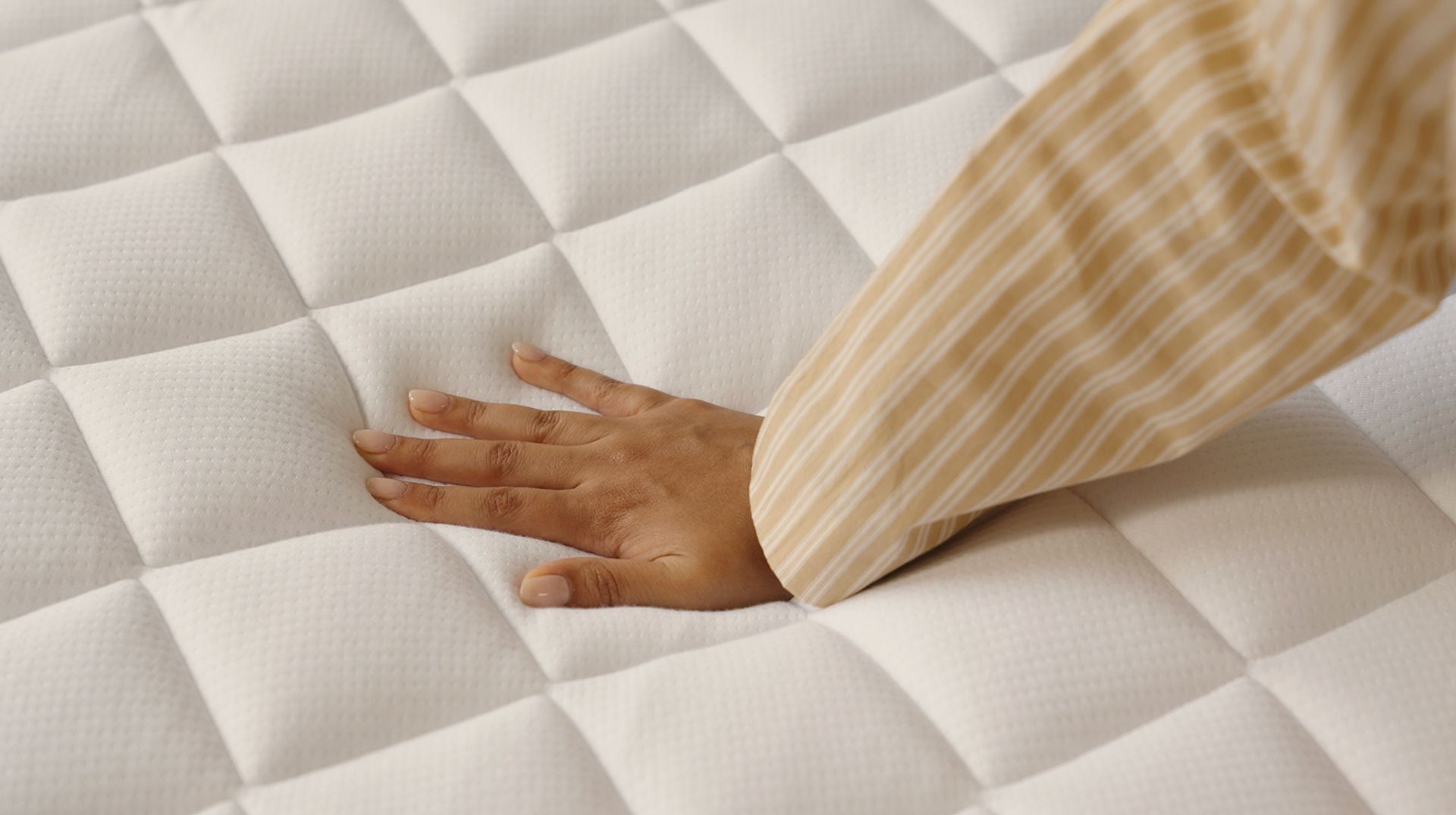 Close up of the surface of a mattress, a hand presses down