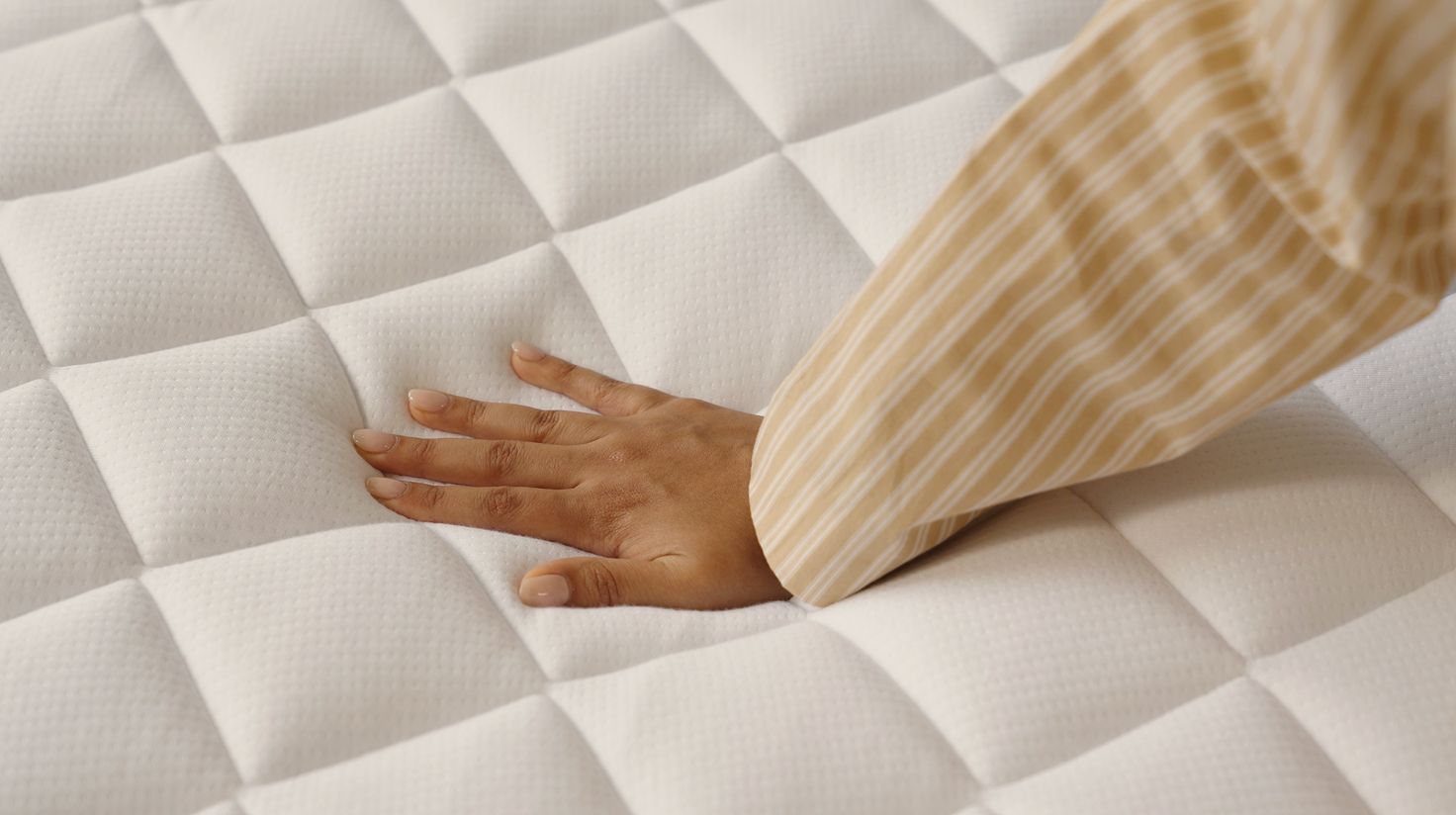 Close up of the surface of a mattress, a hand presses down