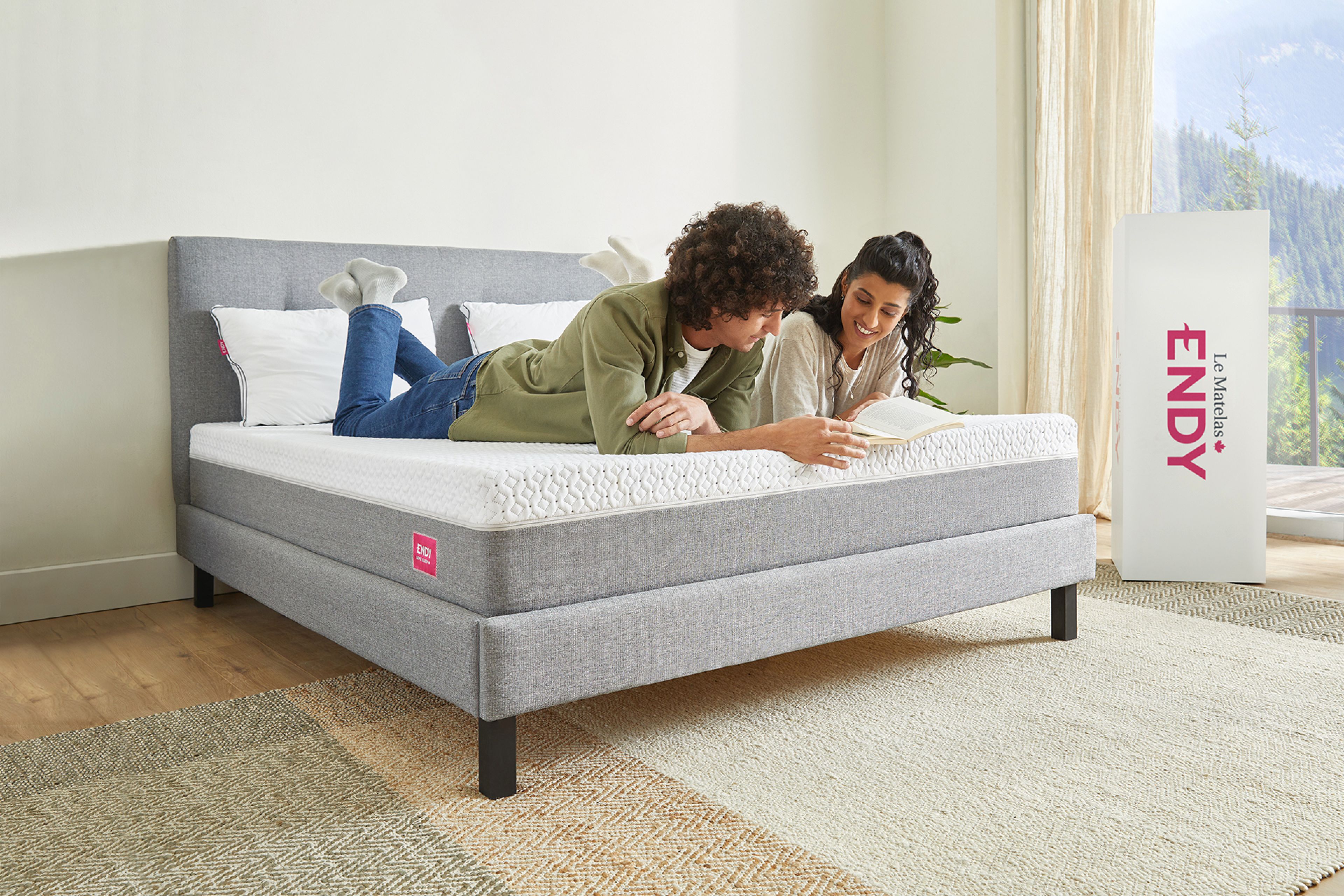 Man and woman laying on their stomaches on a bare Endy Mattress reading a book