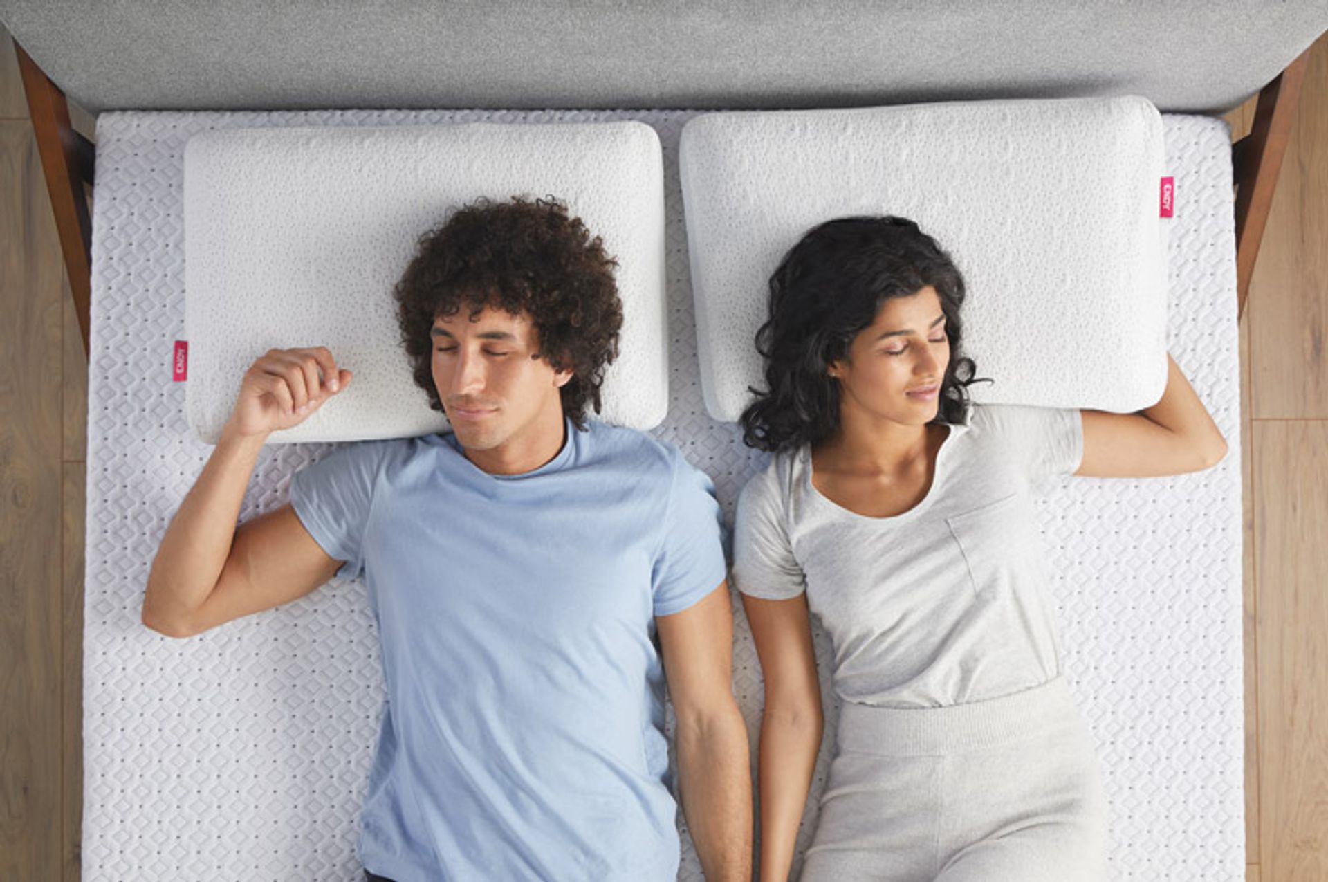 Two people relaxing in a bed outfitted with Endy's collection of sleep products.