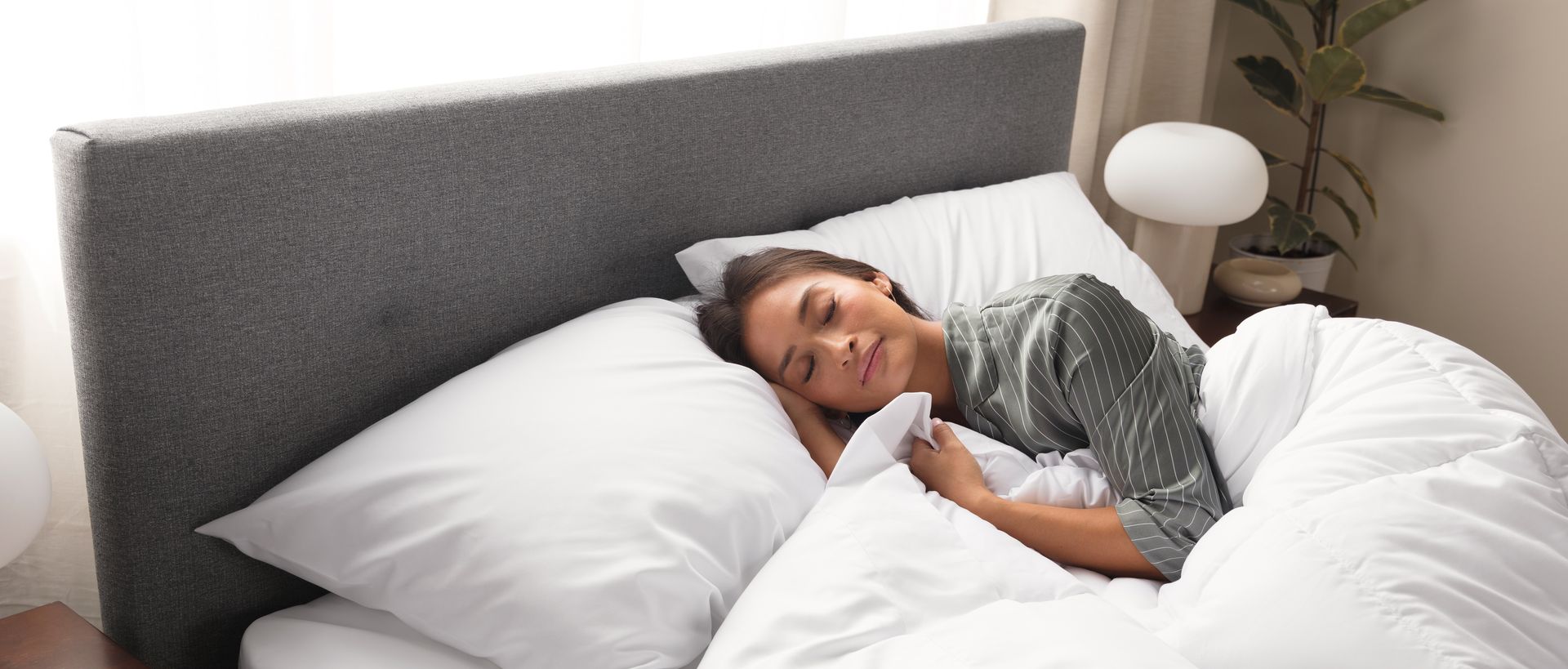 Woman sleeping peacefully under plush white duvet and pillows
