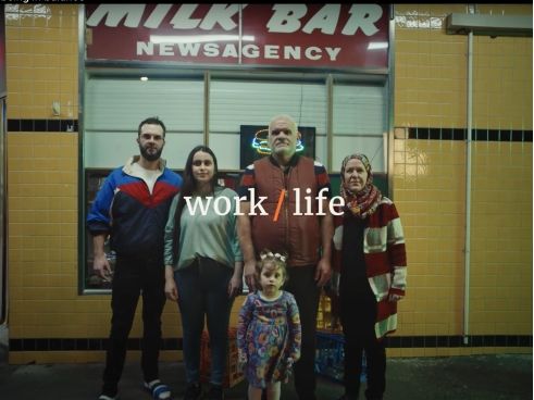 A still from the Australian Unity Being in balance campaign film. Shows a family of 5 standing in front of a retro milk bar. The words work / life are overlayed in the middle of the still.