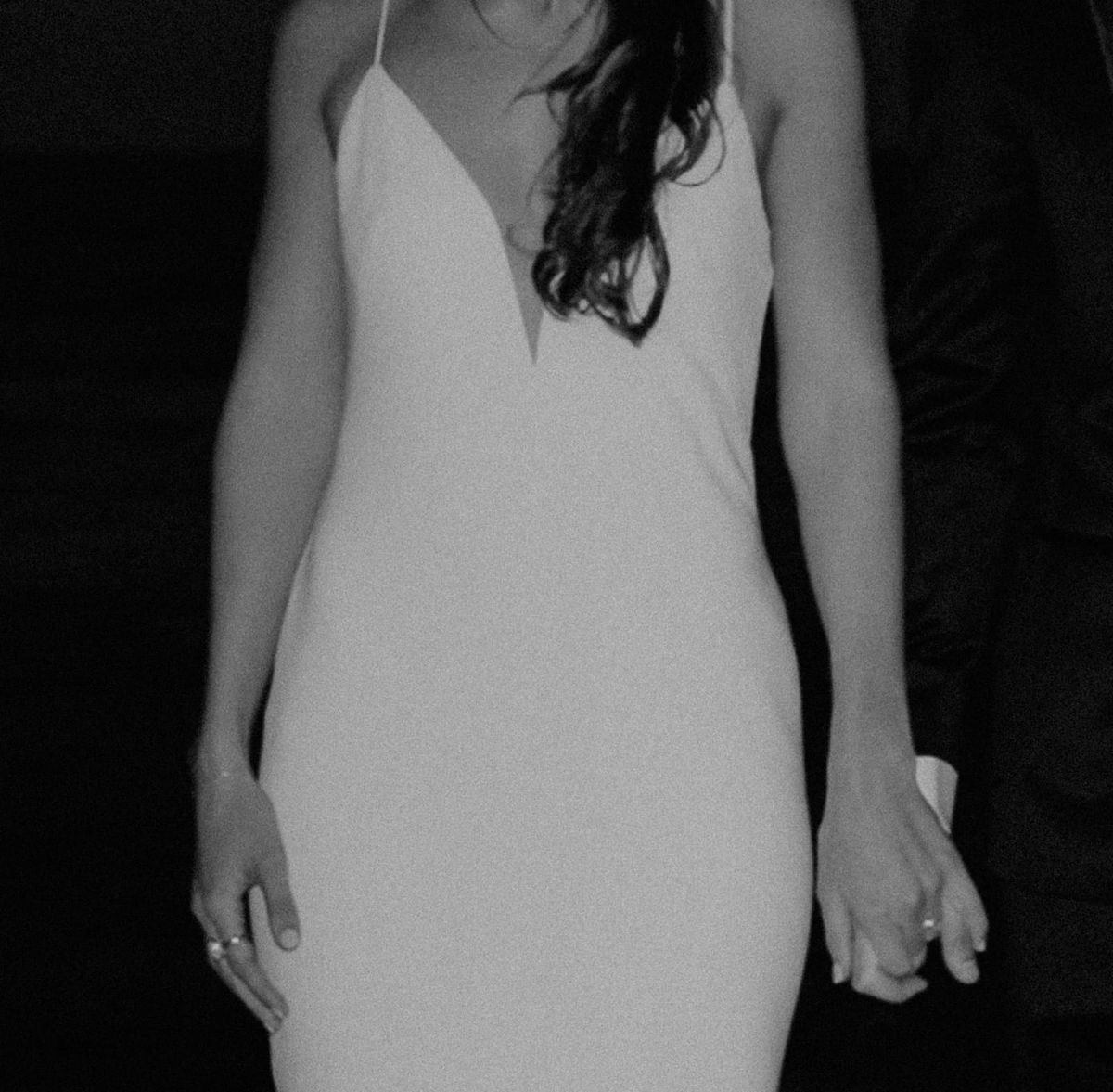 A woman in a white evening dress holding her partner's hand