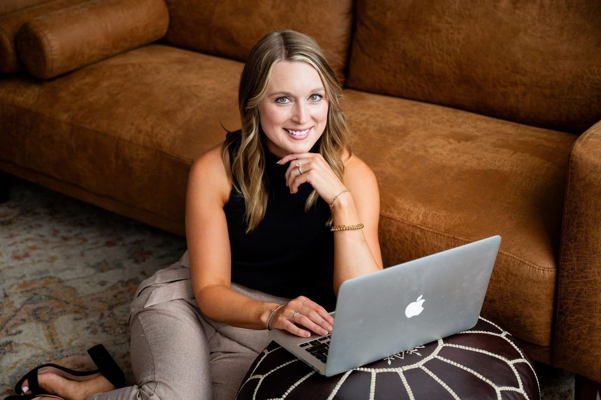 Skylar Lewis sitting on the floor with her laptop, smiling