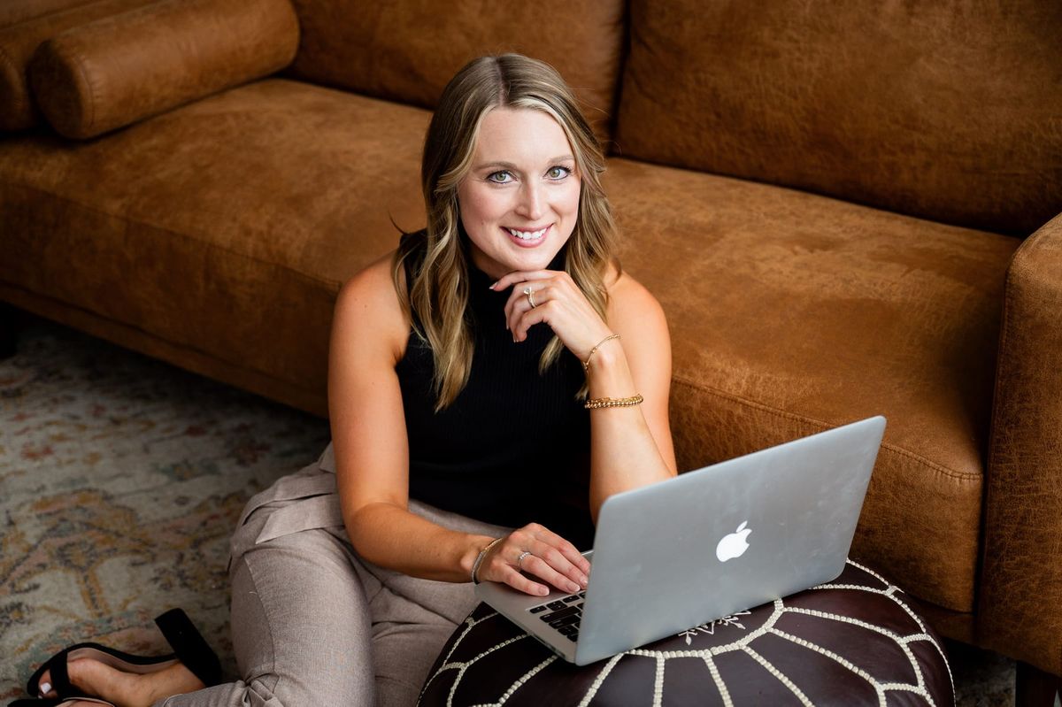 Skylar Lewis sitting on the floor with her laptop, smiling