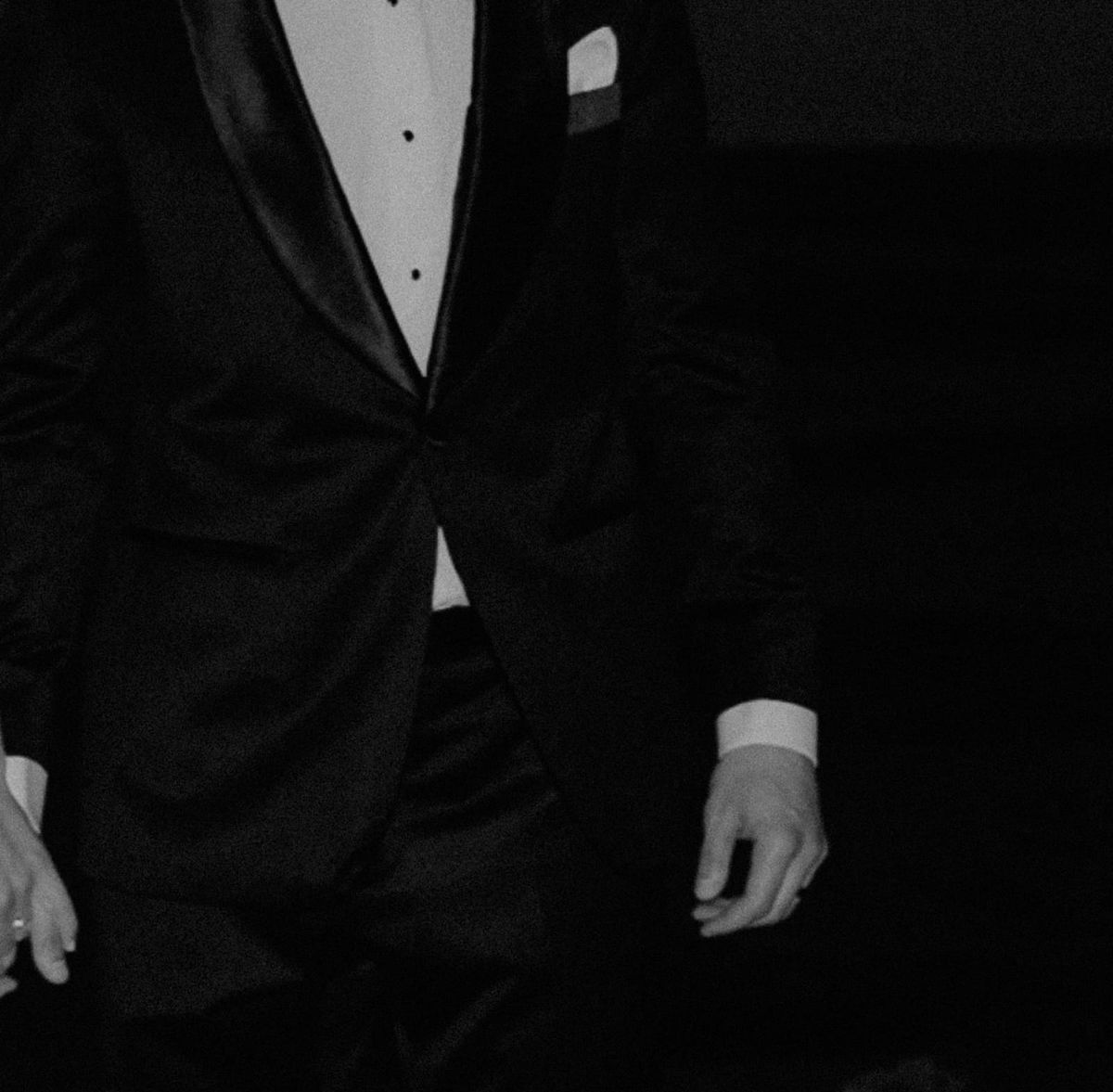 A man in a tuxedo holding his partner's hand