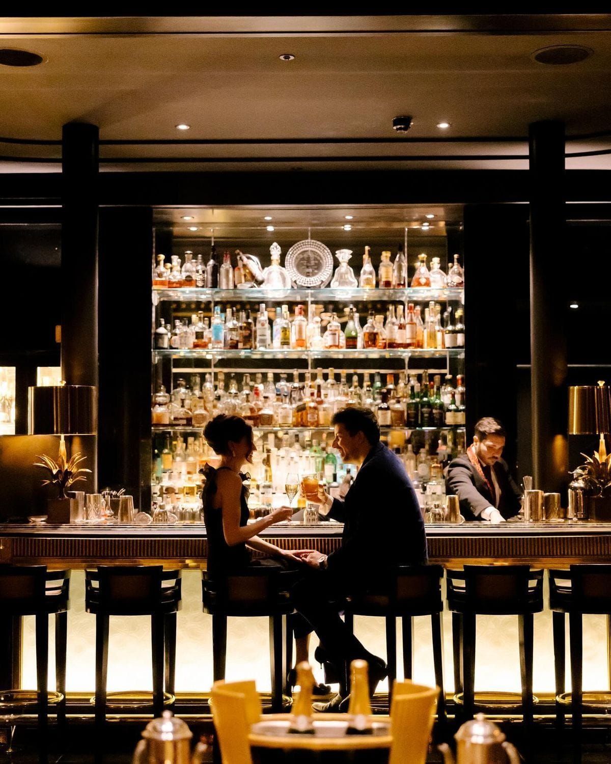 A couple sharing drinks at a candlelit cocktail bar