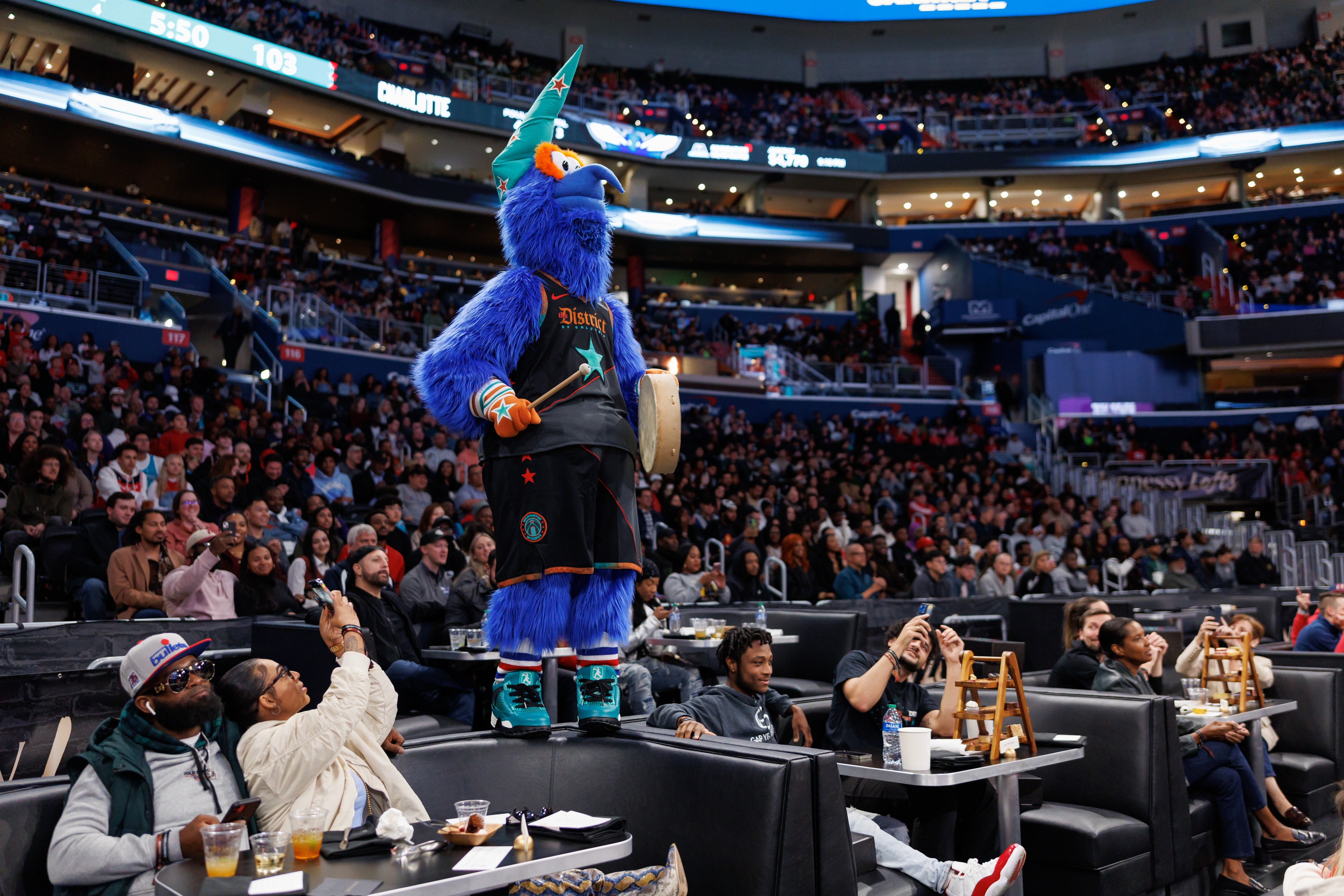 vip crowd eating, drinking and taking photos of the Washington Wizards Mascot from the VIP Hennessy Lofts at the The Capital One Arena