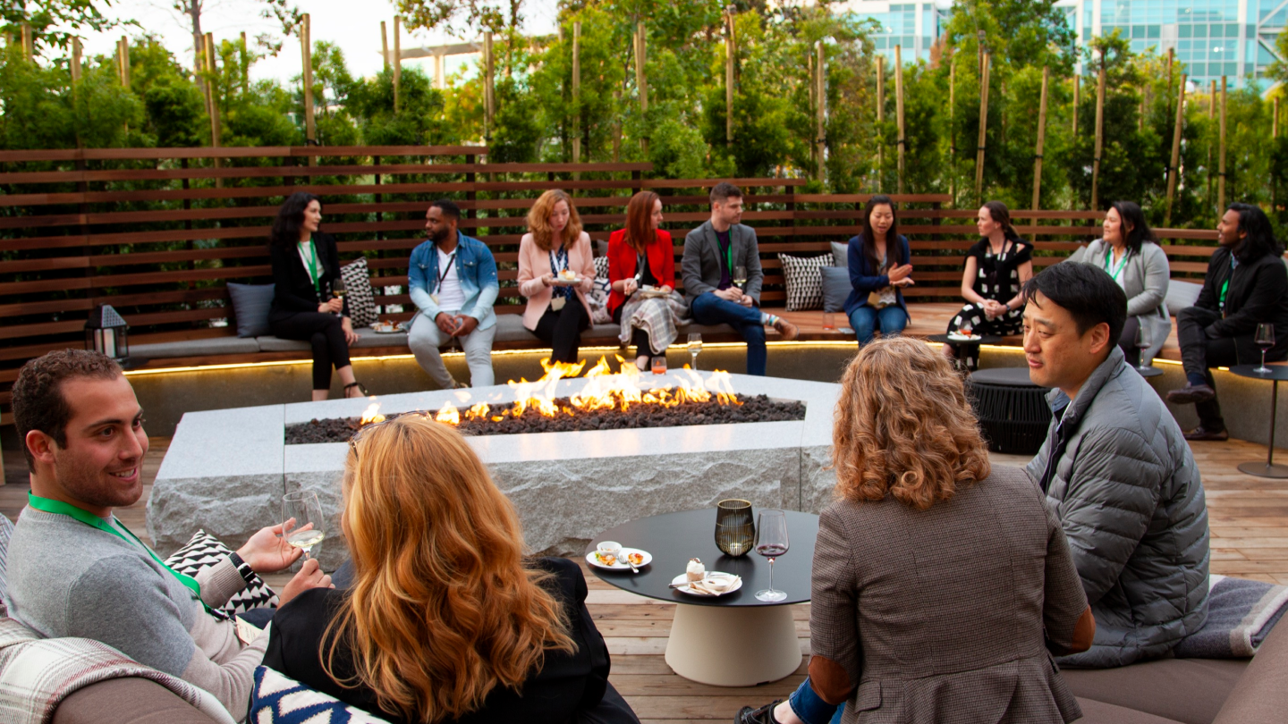 people sitting around outside fire pit having conversations with each other