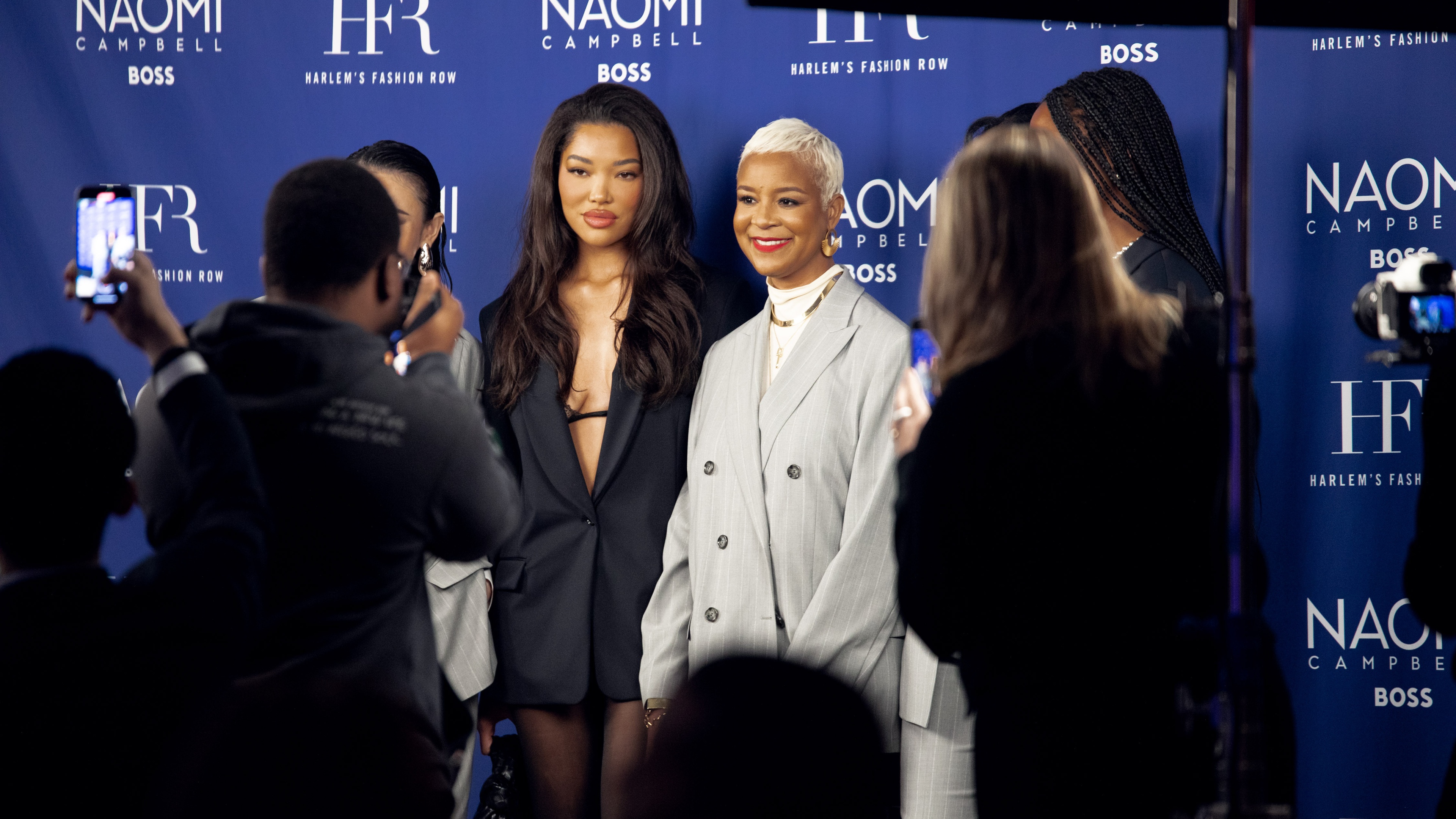 Women posing at step and repeat with photographers