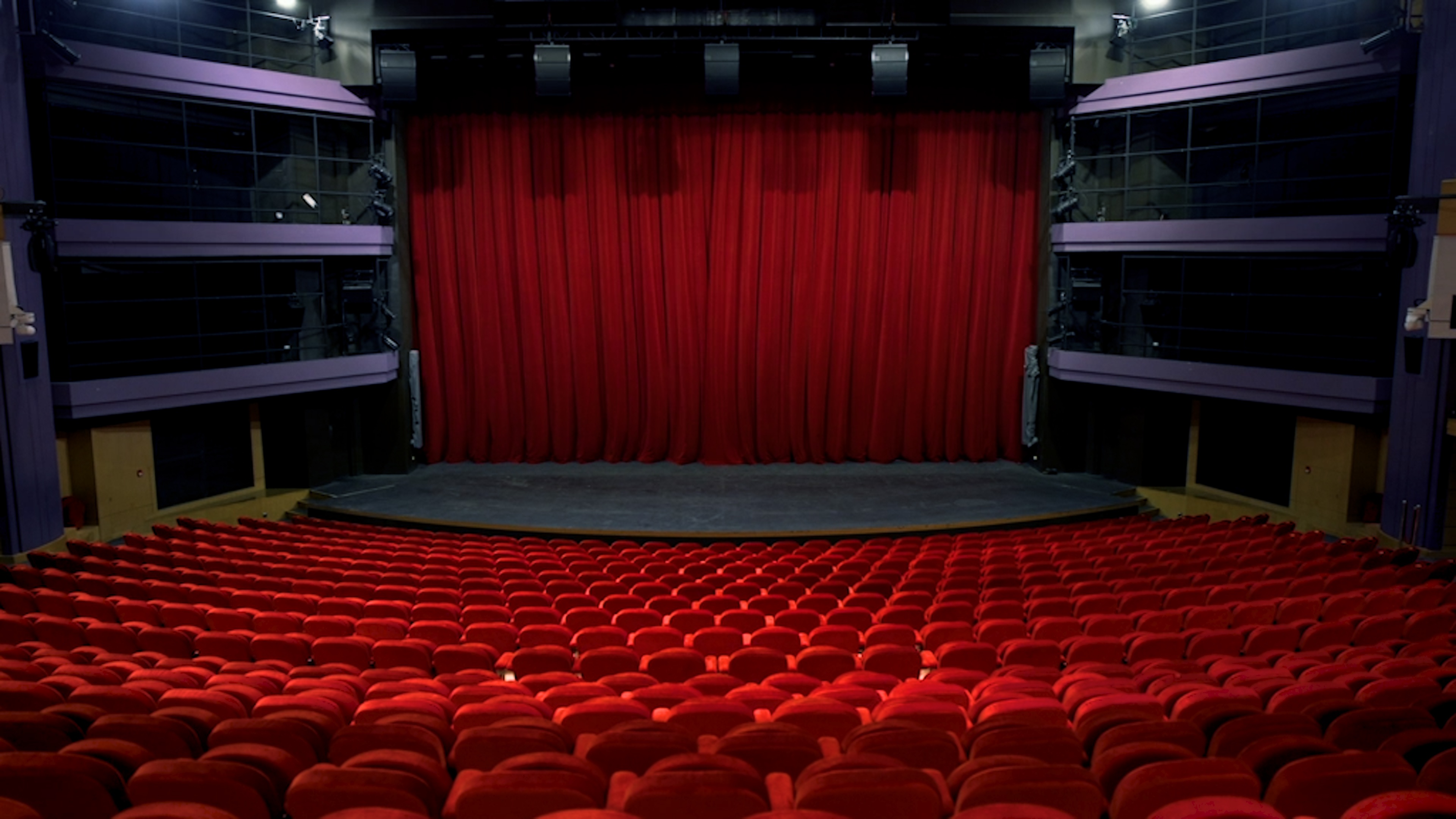 Yuen Long Theatre stage with red drapes and red theatre seating