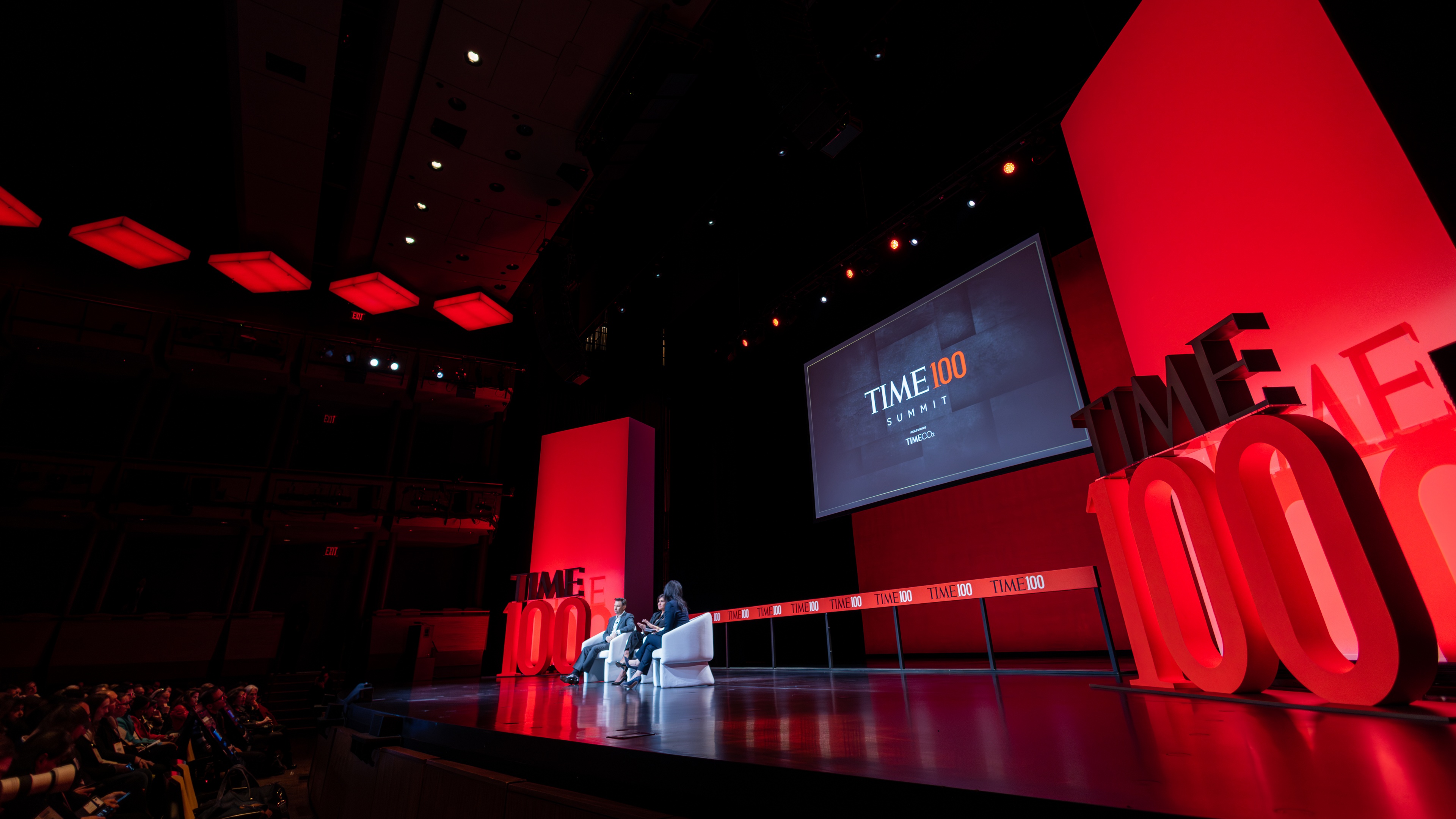 Two people sitting on white chairs on stage at the TIME100 Gala