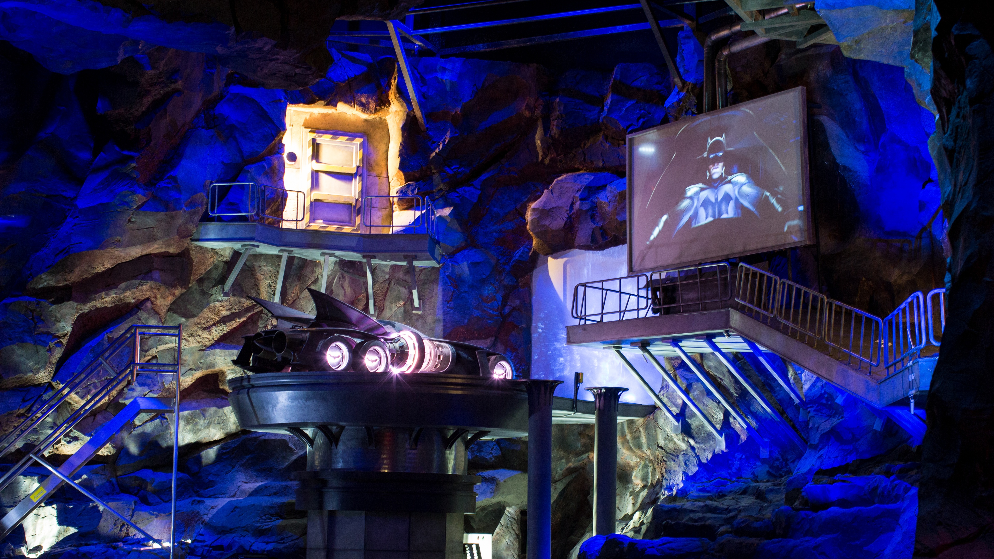 Indoor canyon ride with blue lights and LED screens showing Batman