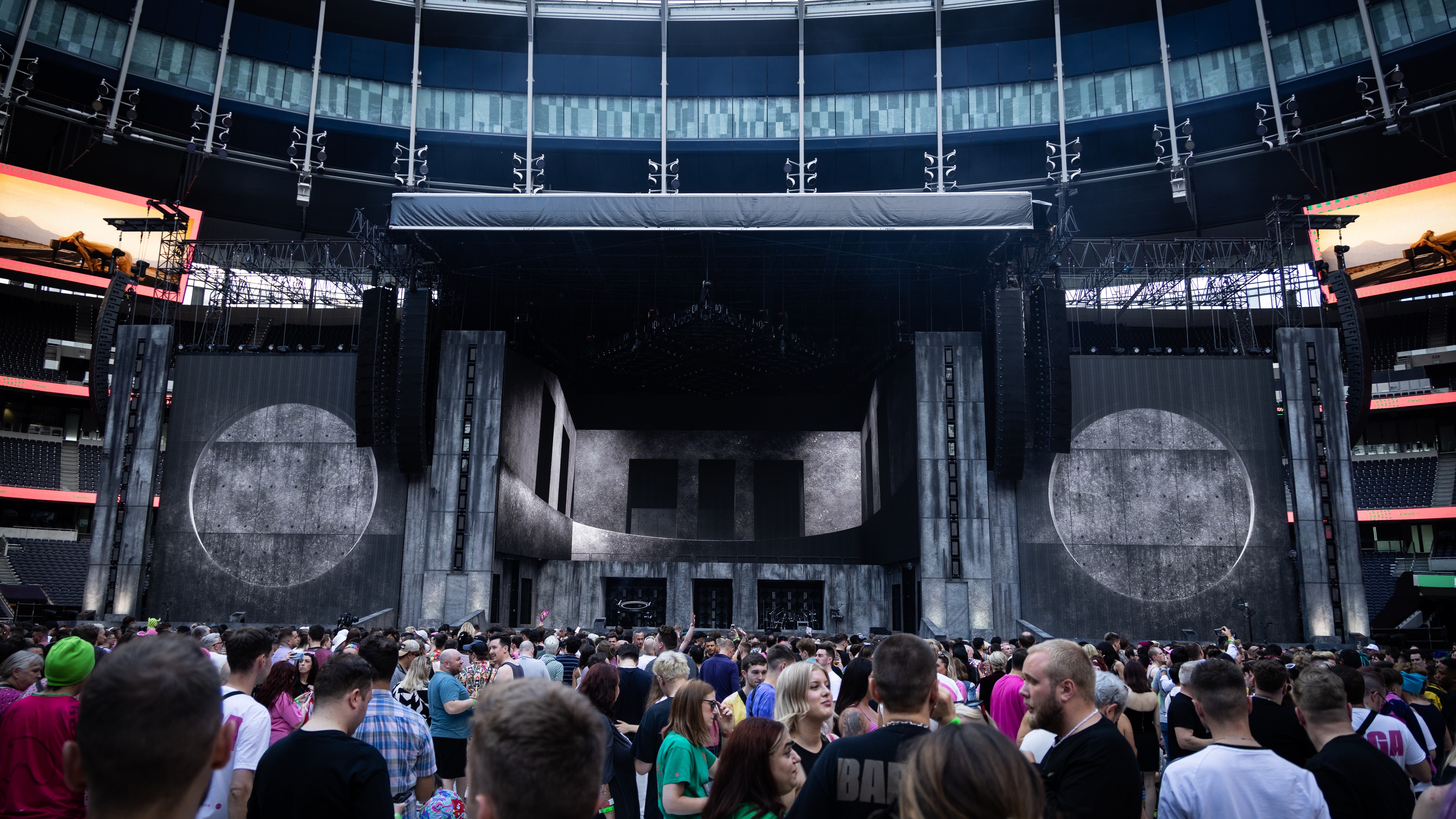 Crowd waiting for performance in football stadium with huge concrete staging and LED screens