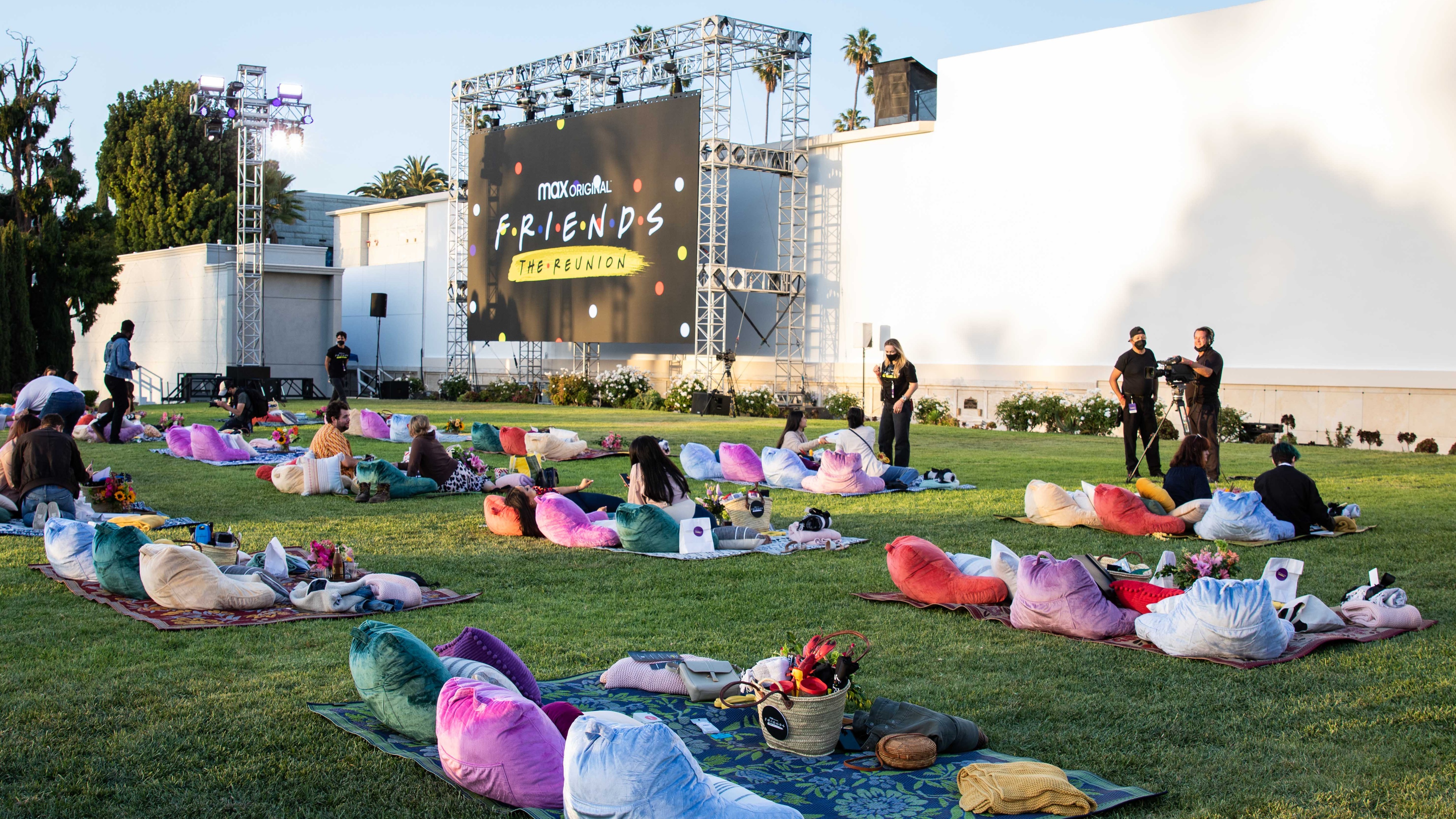 People sat on beanbags on blankets on grass watching big screen playing Friends