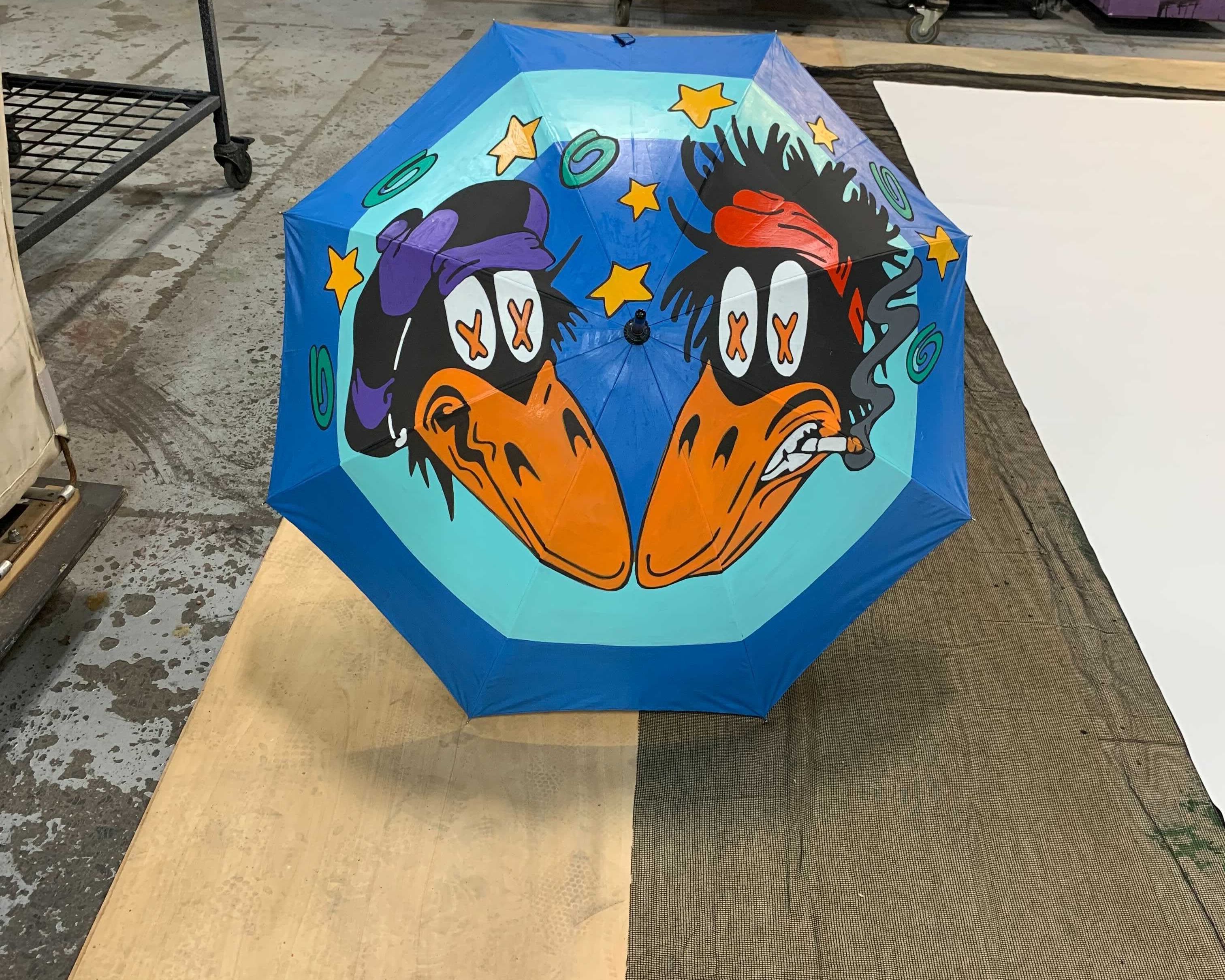 umbrella illustration design featuring 2 black crowes, with x'ed eyes, one of them smoking for the Black Crowes Shake Your Money Maker Tour