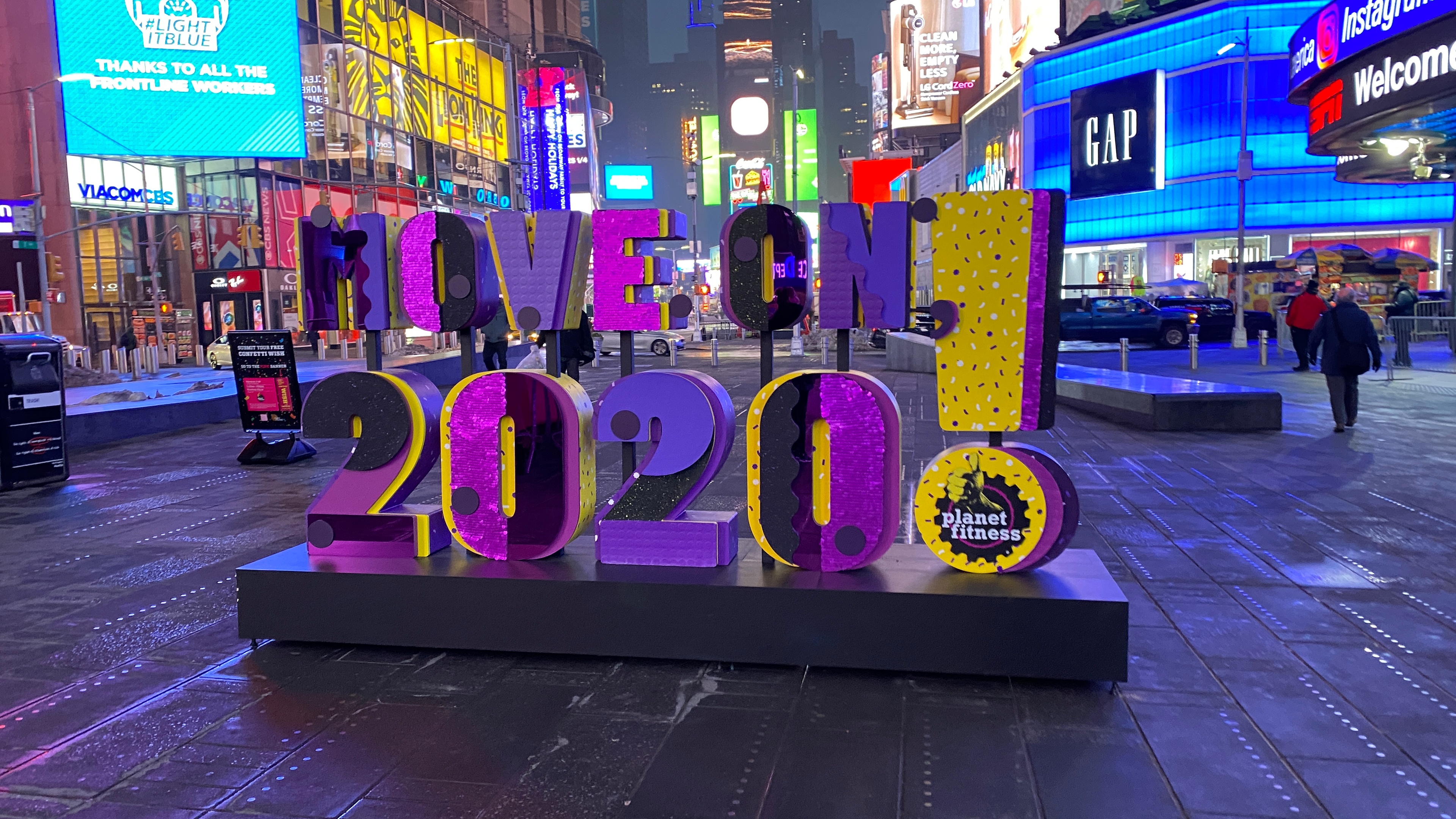 Purple and yellow sign that says Move on 2020! in times square