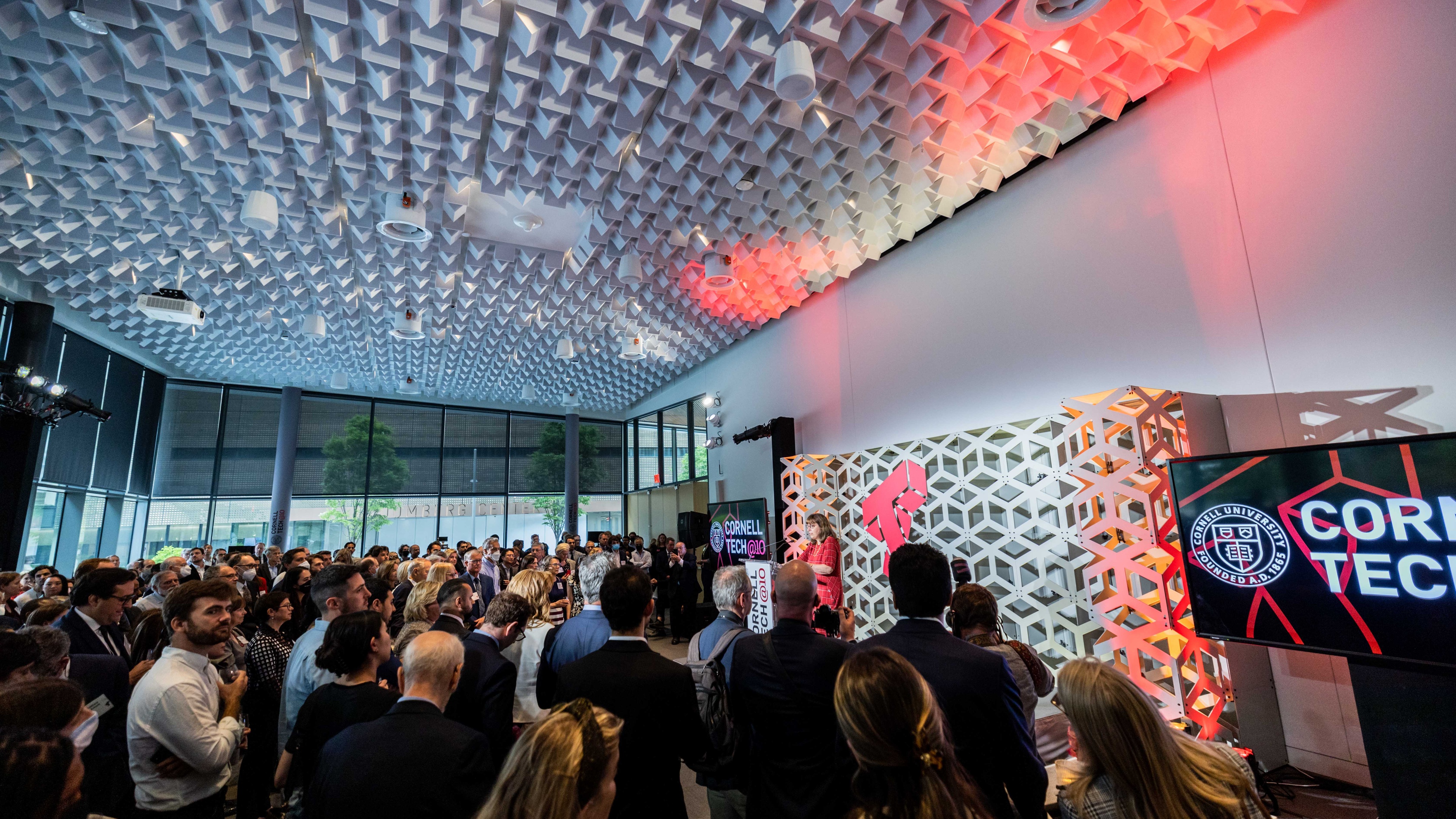 Cornell Anniversary Celebration wide image with guests standing in front of speaker