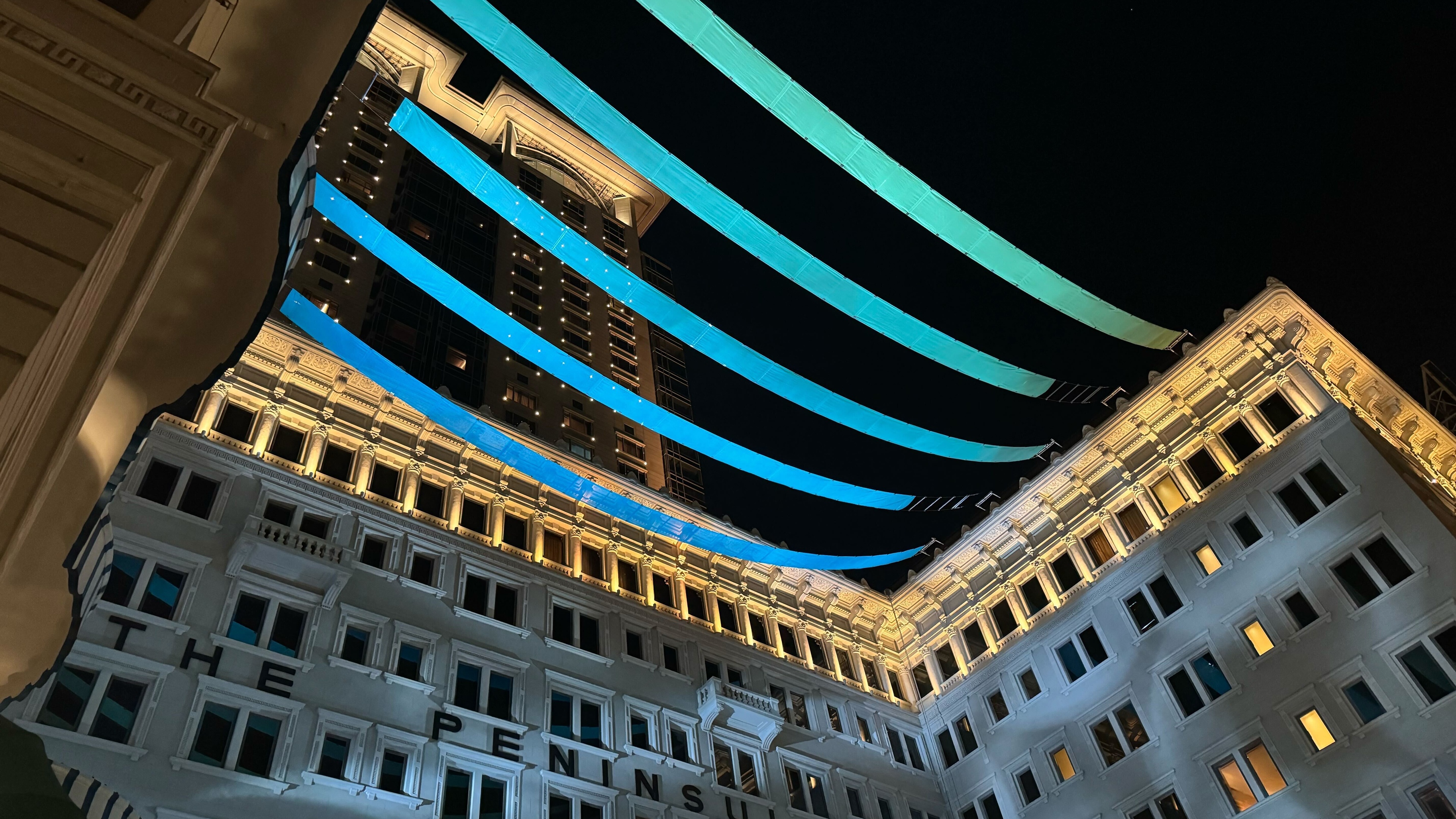 Night time exterior shot of blue banners hung above hotel