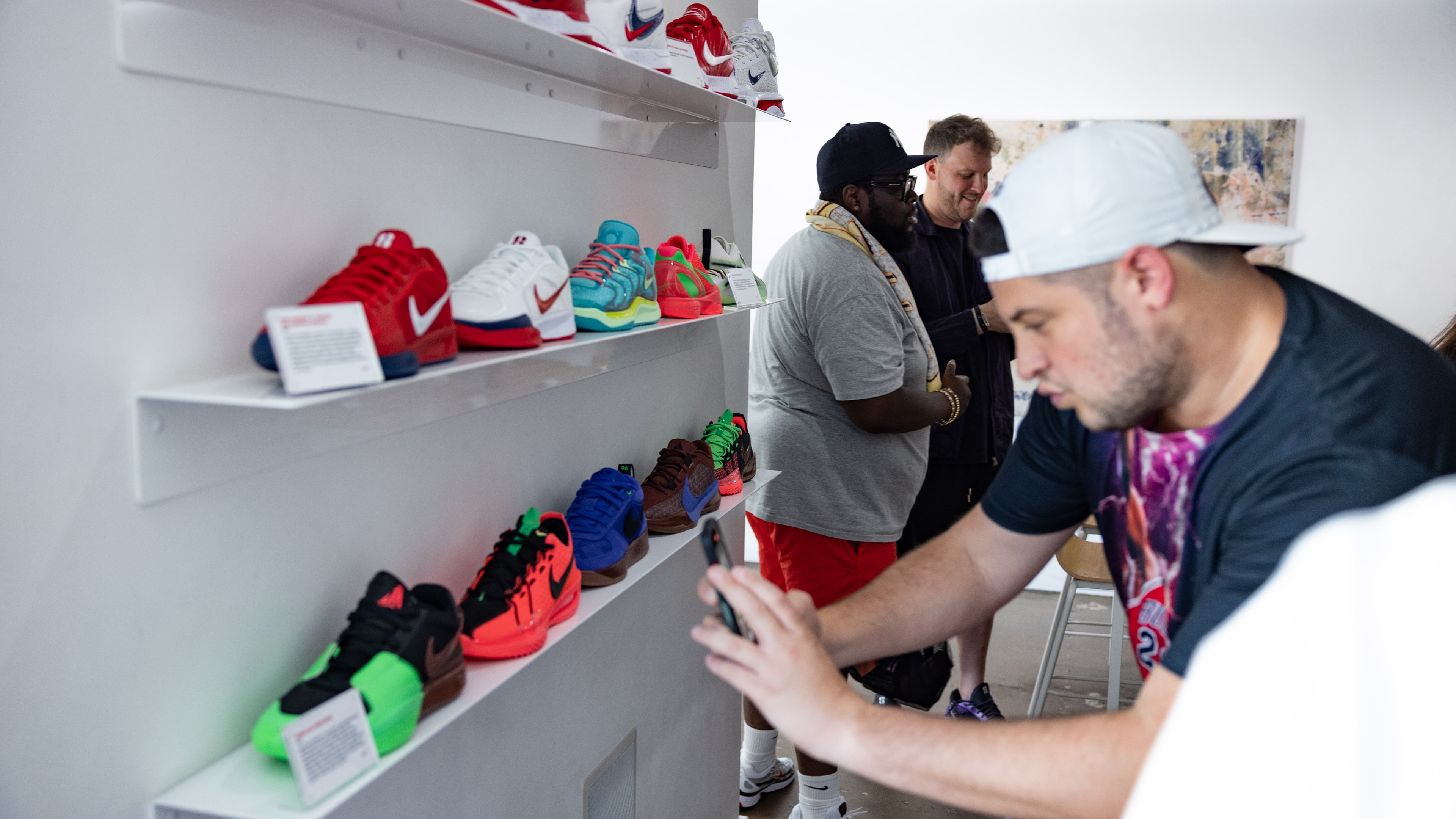 Man taking photo of Nike shoes displayed on wall
