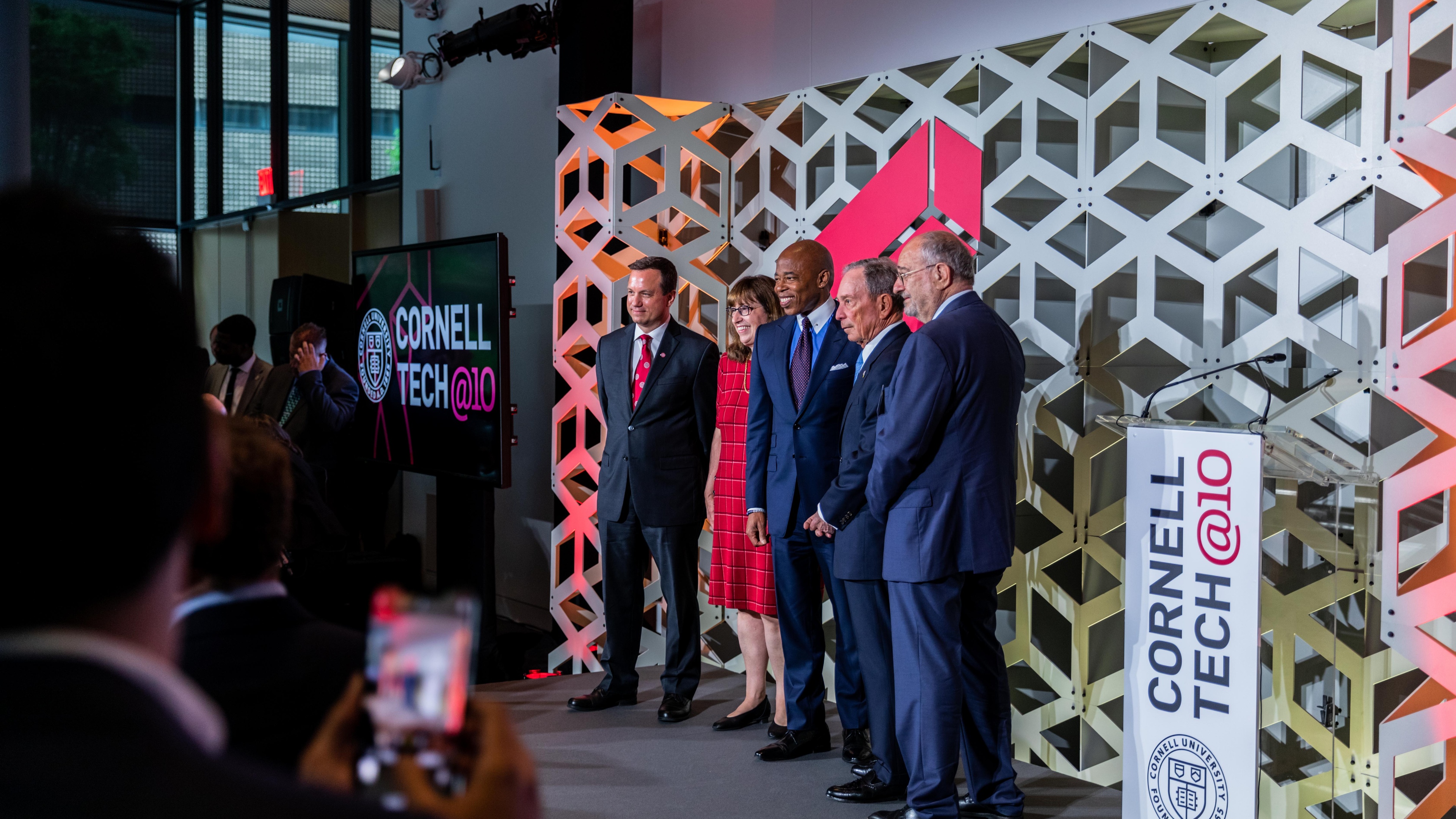 Cornell Anniversary Celebration guests posing in front of step and repeat