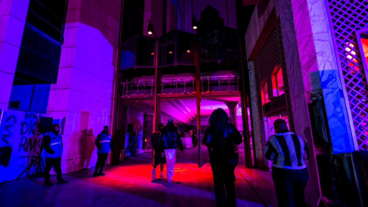 People entering industrial building with red and blue lighting and security