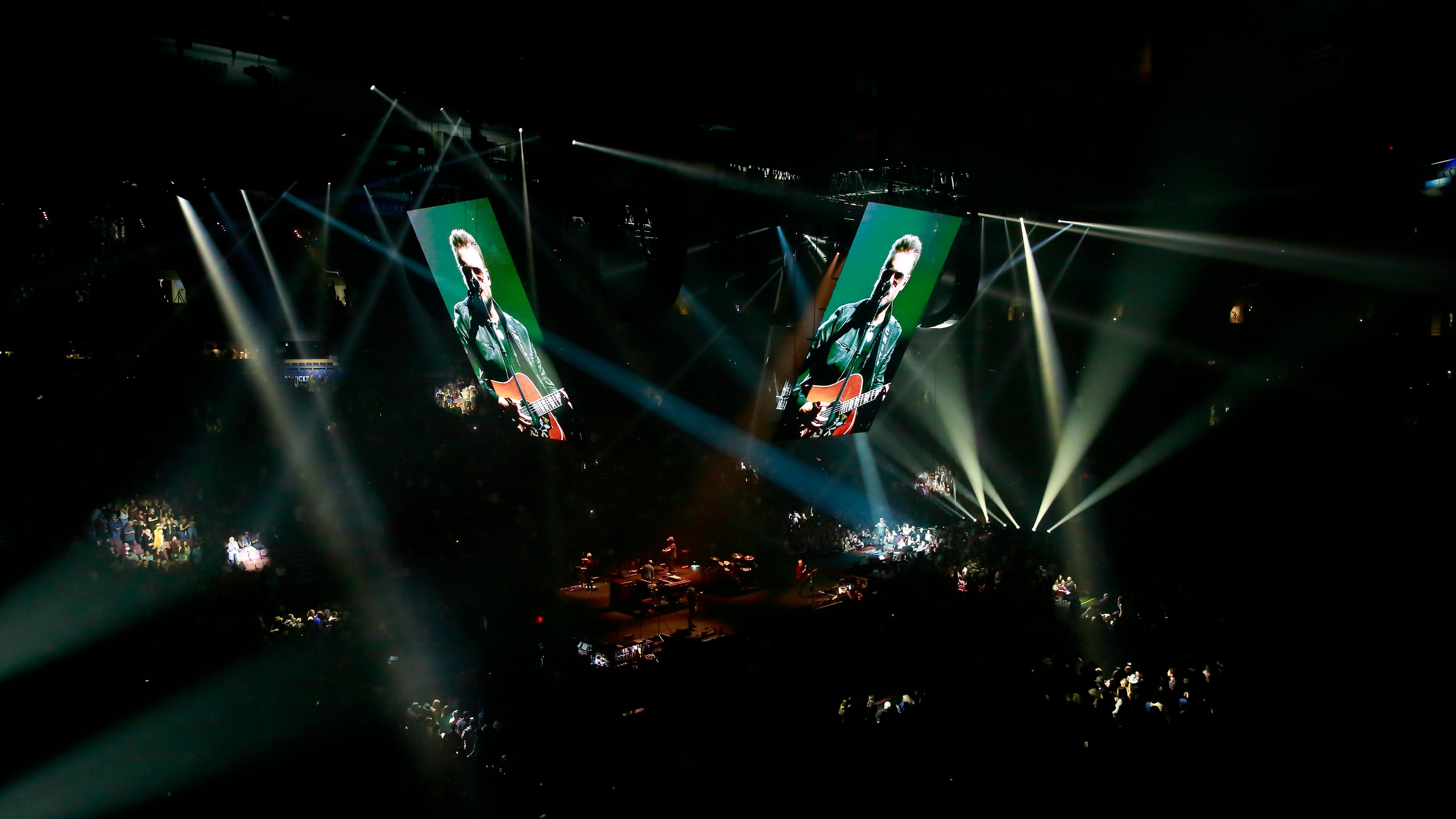 view from the balcony stands showing two screens featuring Eric Church singing and playing guitar in a green backdrop, stage and crowd visible in the background