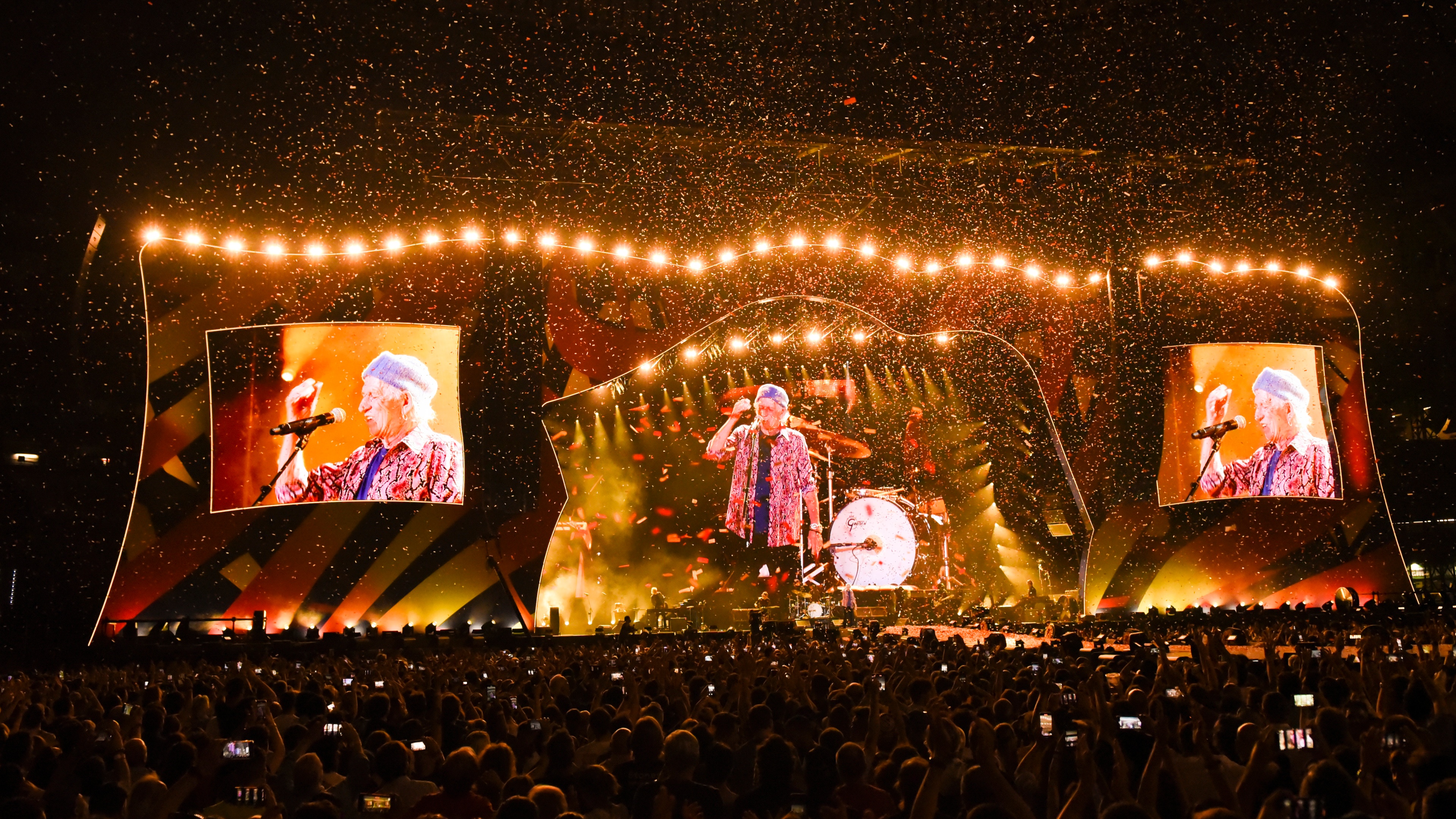 The Rolling Stones playing in football stadium on stage with huge LED screen with band members and spotlights