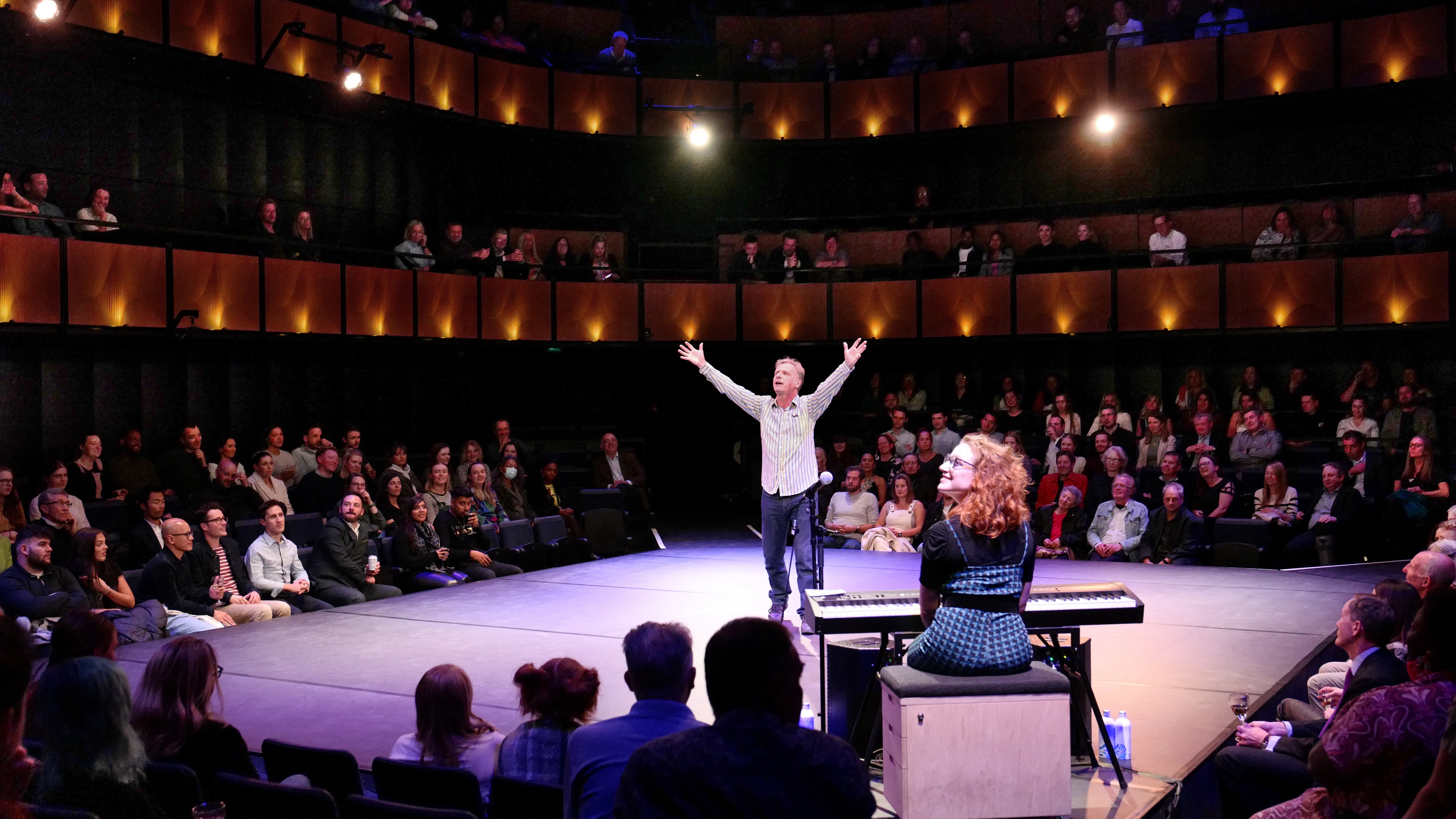 Man with arms raised on stage at @sohoplace