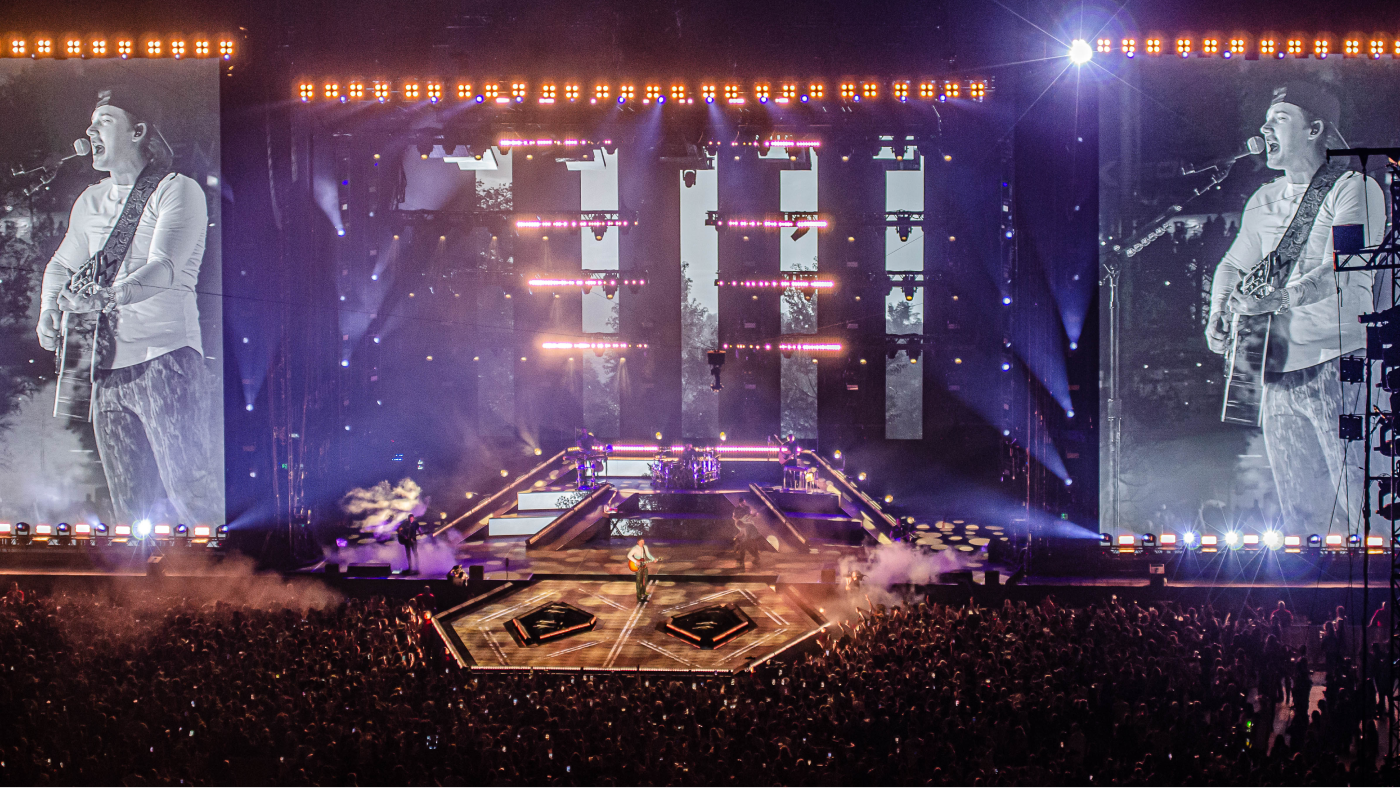 far out view of performers on stage with screens on either side showcasing Morgan Wallen up close