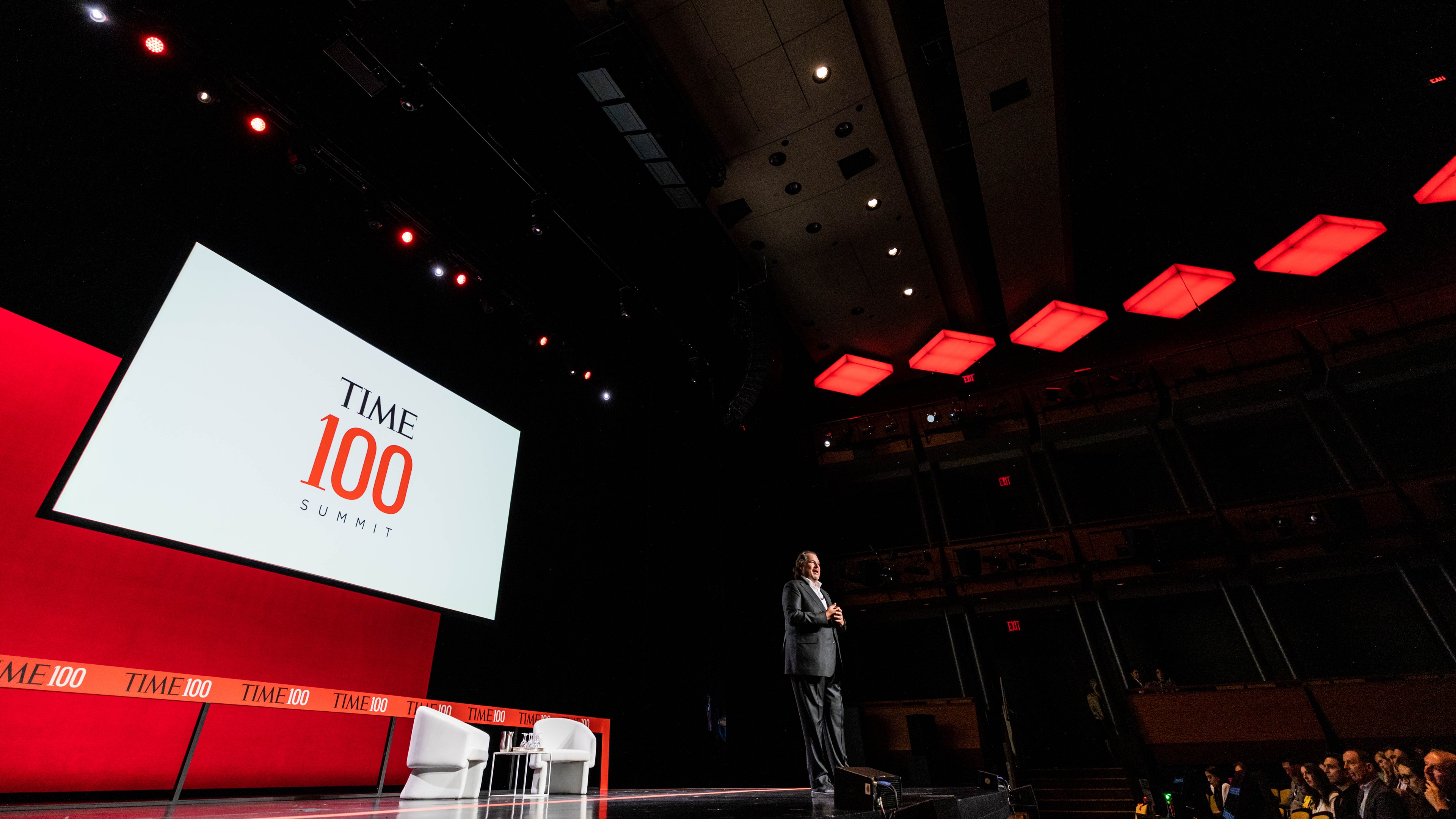 Person on stage with "TIME100 SUMMIT" displayed on a screen behind them