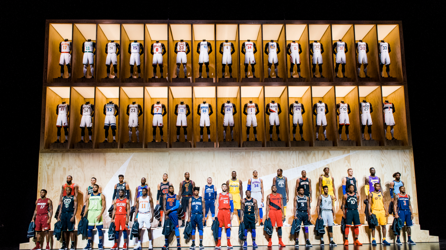 full view of nike uniform display showcasing uniforms on mannequins with player sin uniform standing below