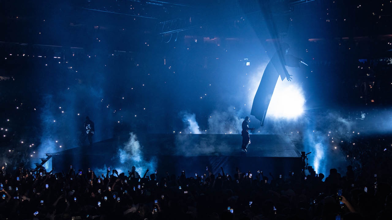 Rapper Drake performing on stage lit blue with smoke
