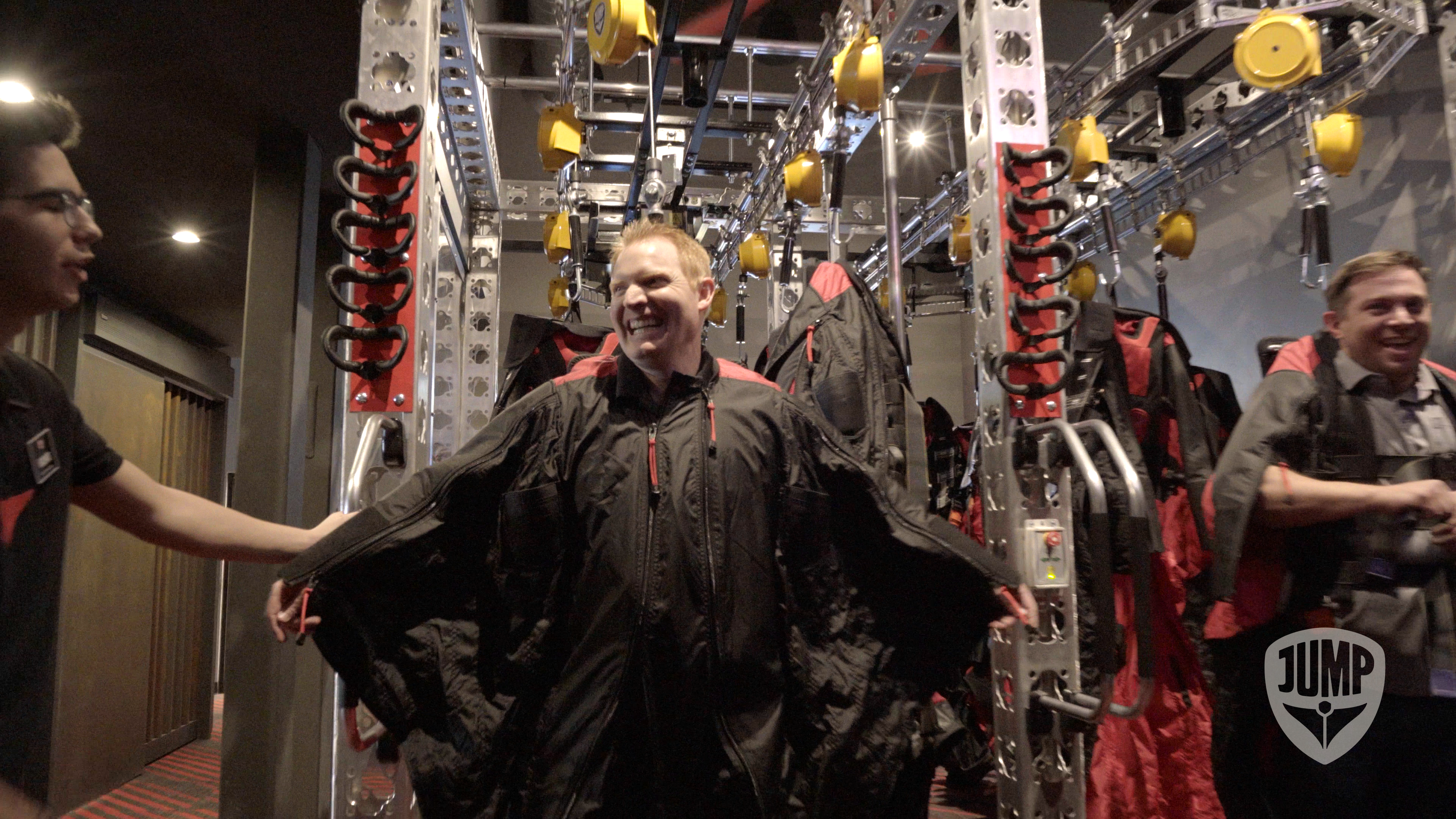 Man smiling and getting prepped in wing suit for virtual simulator