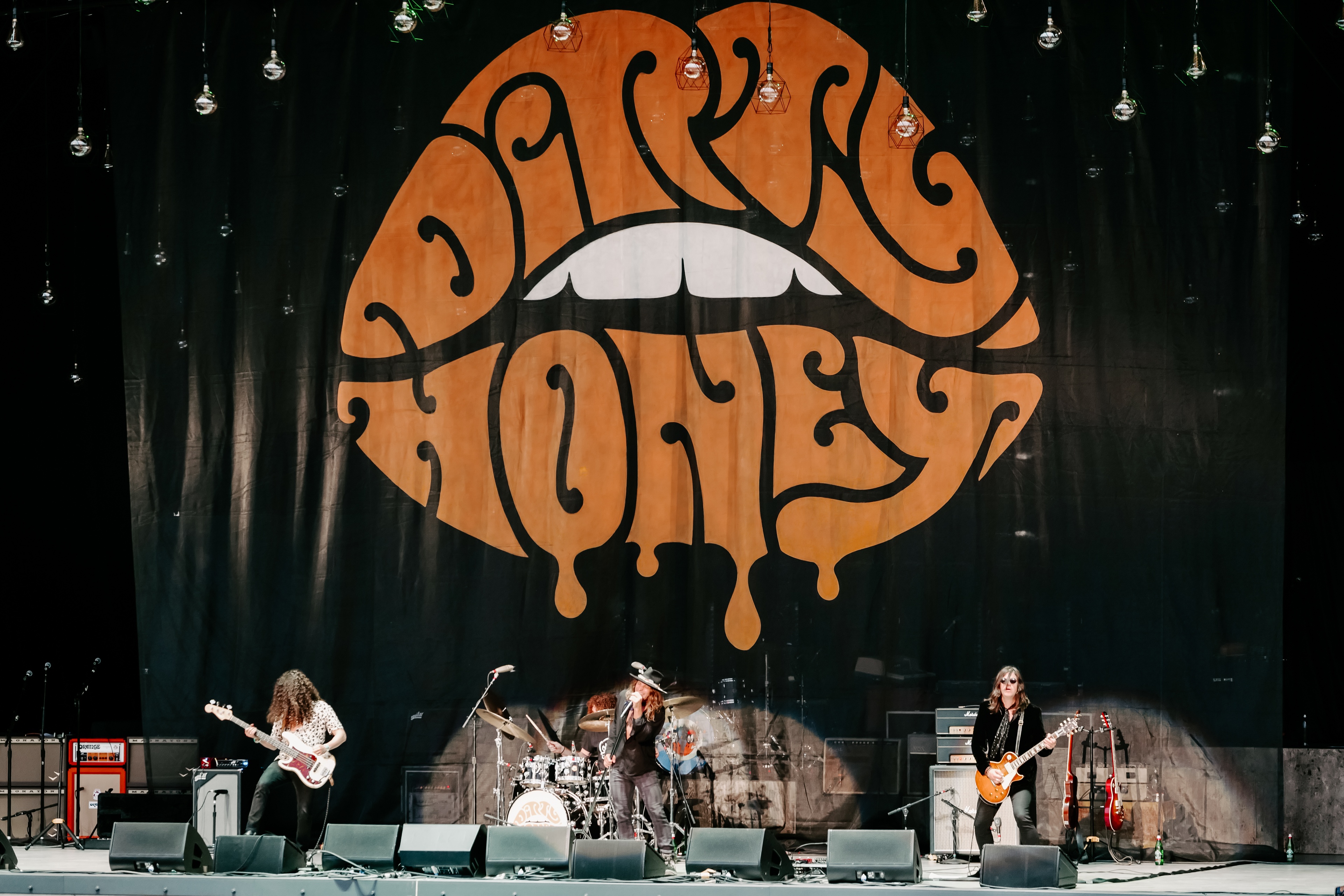 Black Crowes performing on stage at the Shake Your Money Maker Tour backdrop features a psychedelic orange mouth with lips that spell dirty honey