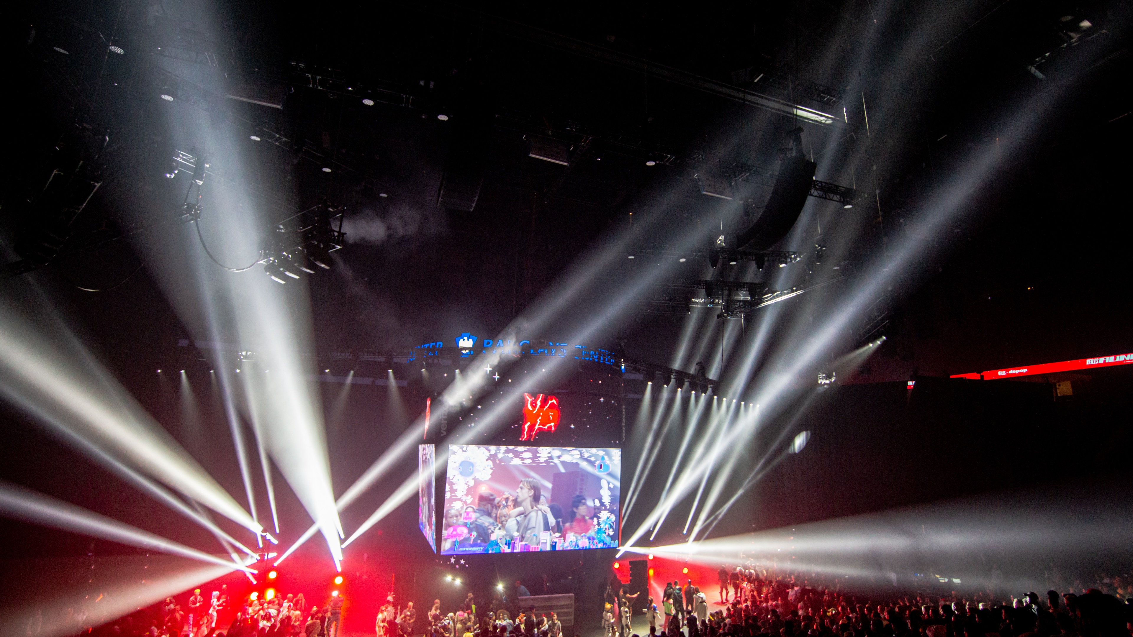 Large LED screen above crowd with red and white lights