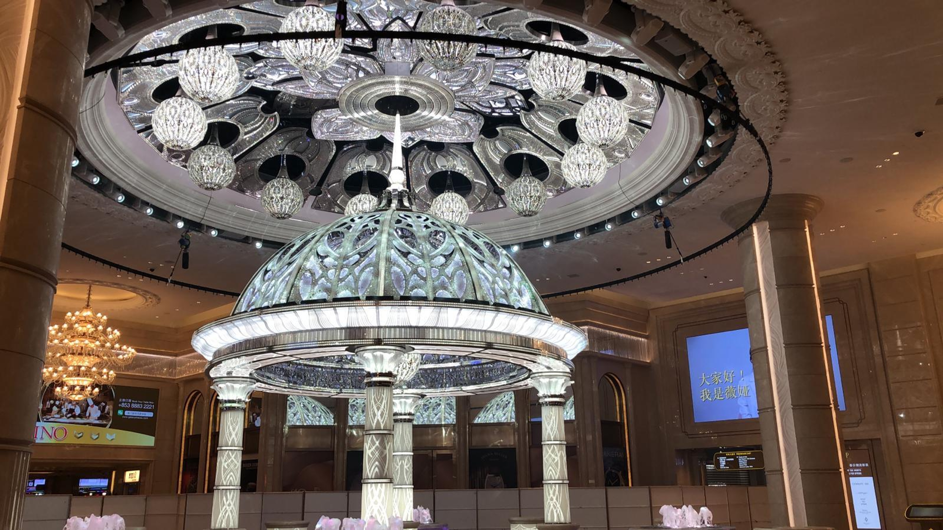 Architectural kinetic Lous flower sculpture installed in centre of grand lobby with chandeliers and light displays