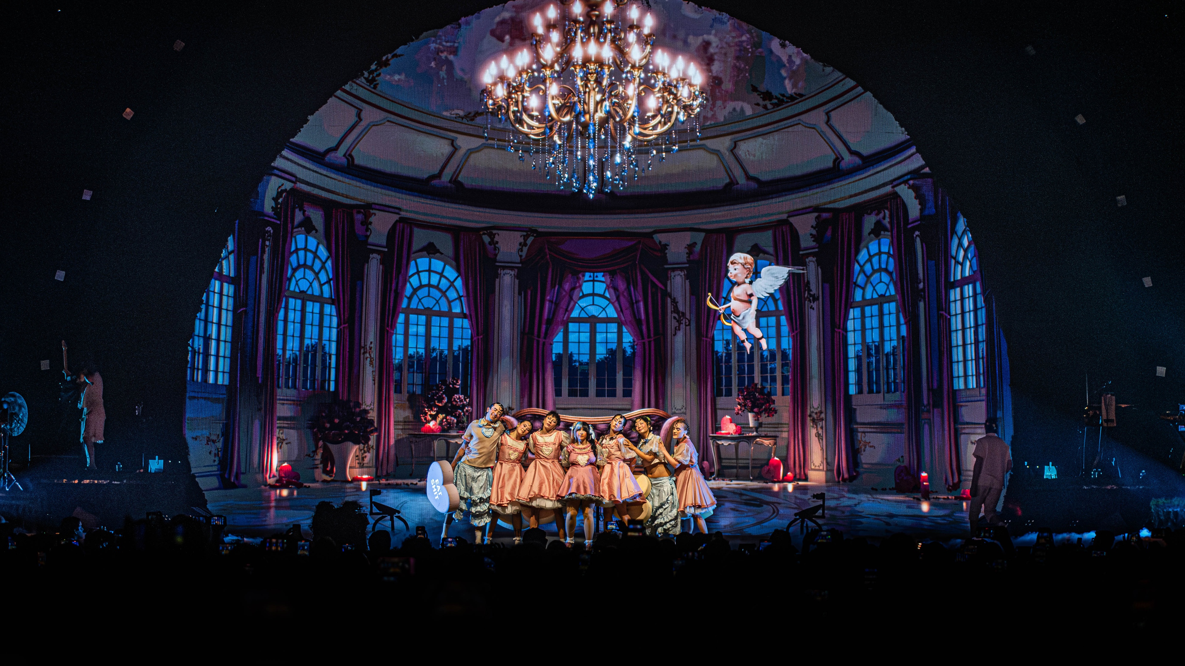 Stage with performers standing in line and colonial building in back
