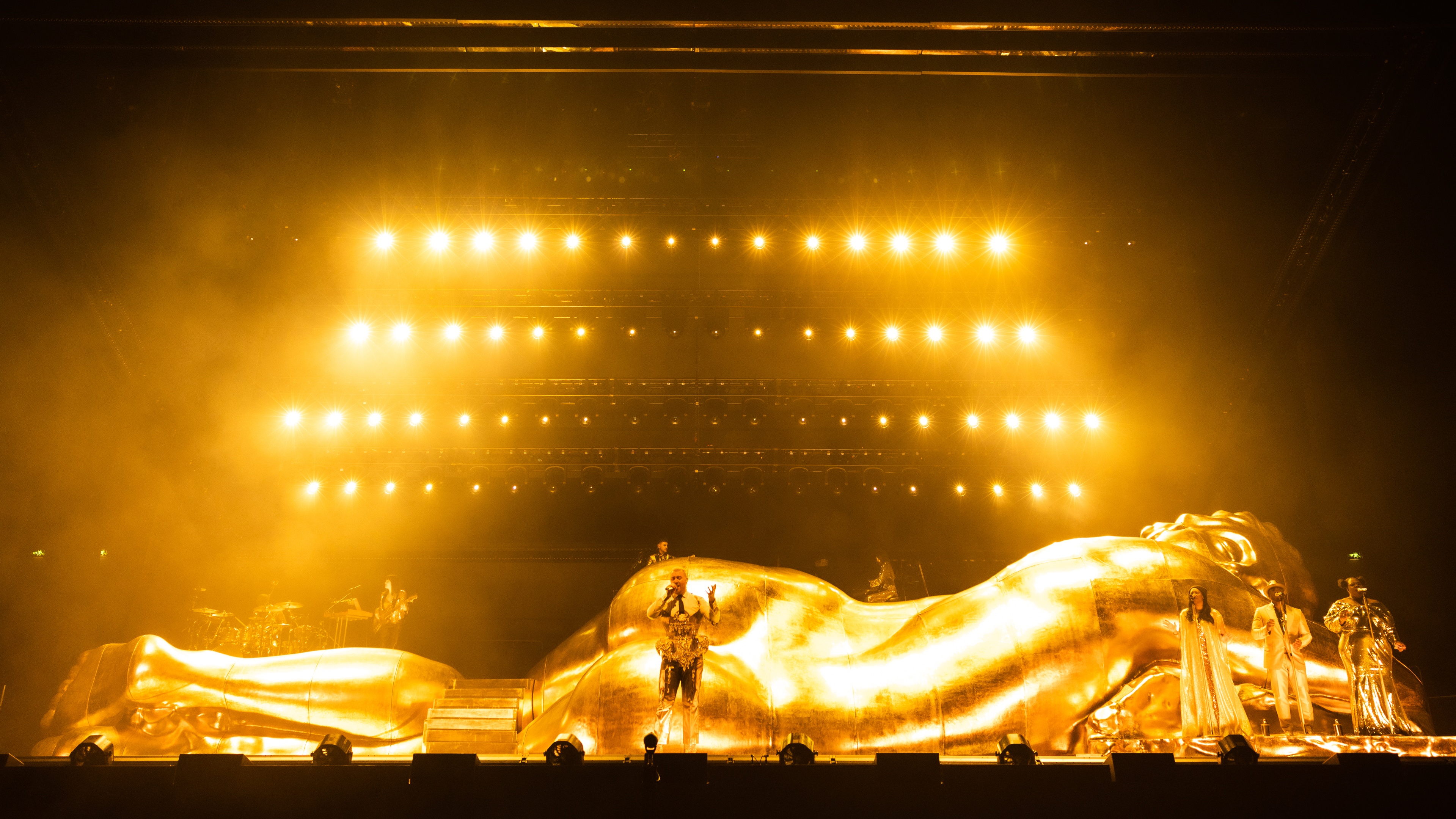 sam smith on stage in front of gloria sculpture with gold lights