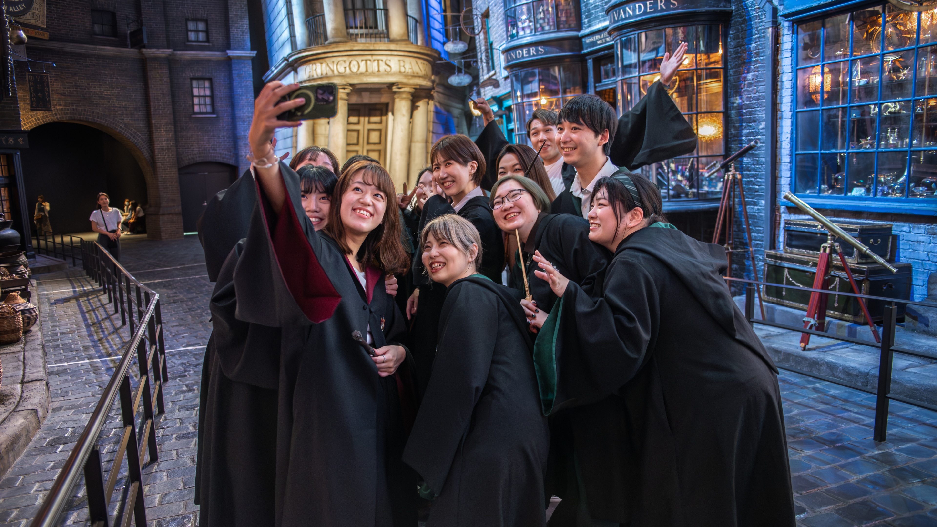 People gathering to take a selfie on Diagon Alley in Harry Potter costumes smiling