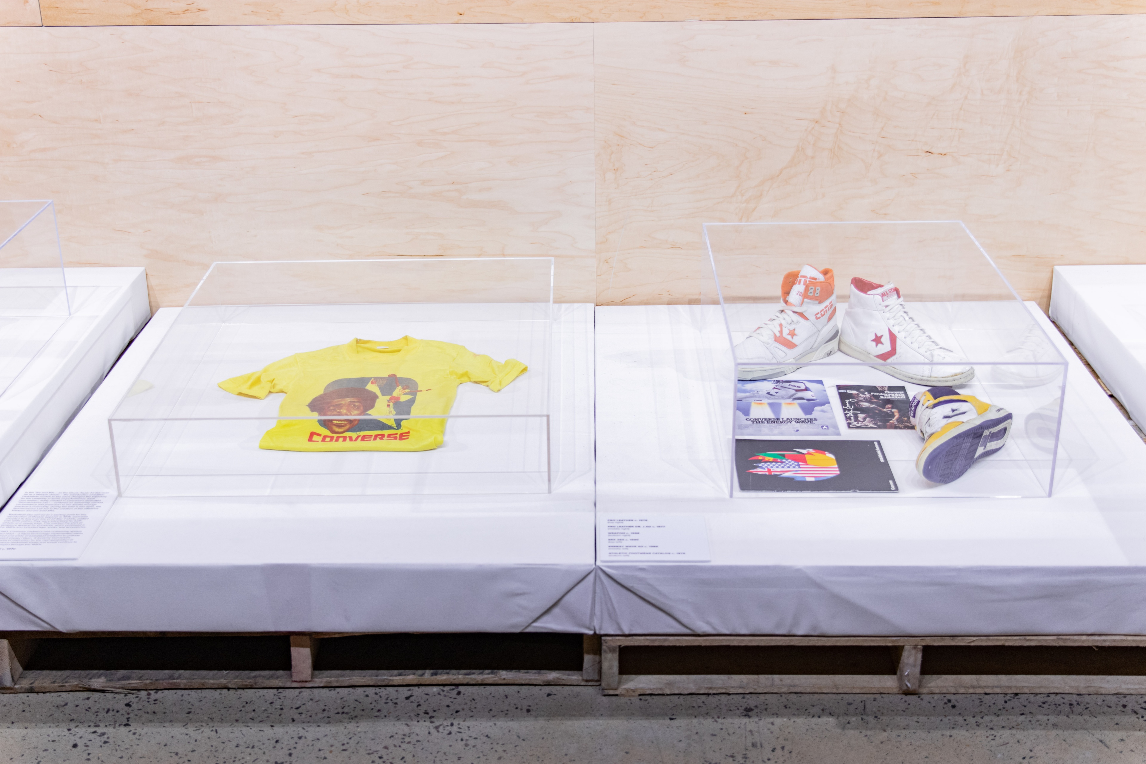 Glass case with yellow shirt on left and shoes on right