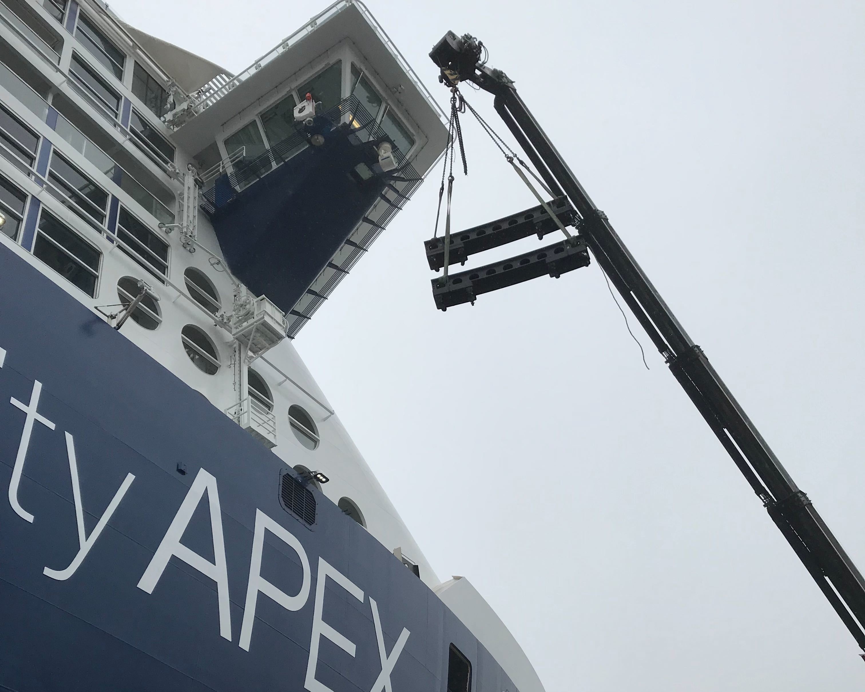 Crane lifting steel cars onto a cruise ship