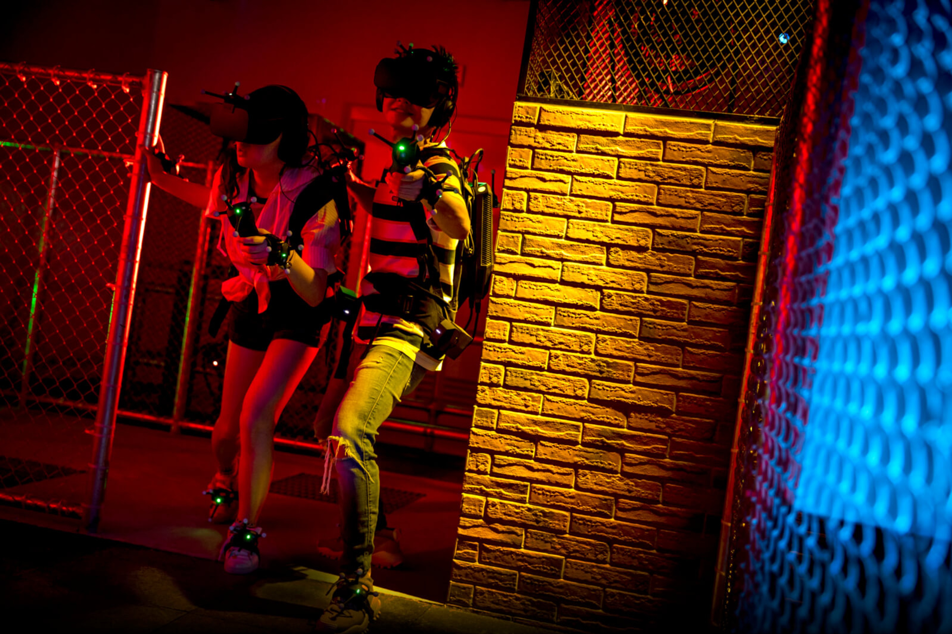 Children playing VR assault course games wearing headsets and walking through a industrial environment with red lighting