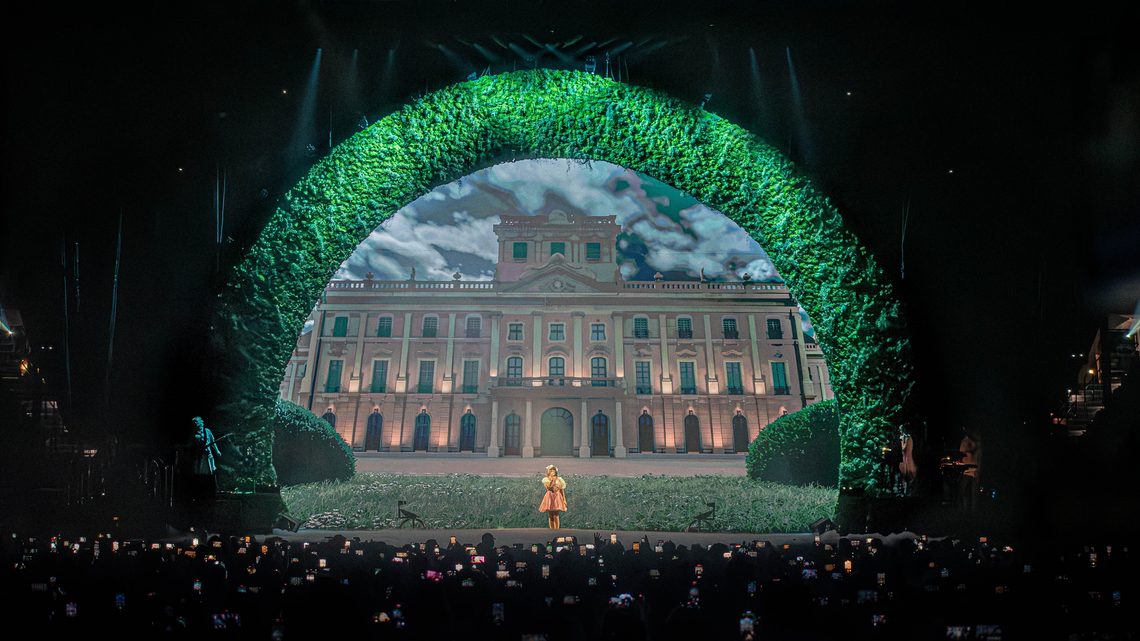 Stage with large plant arch and colonial building in center