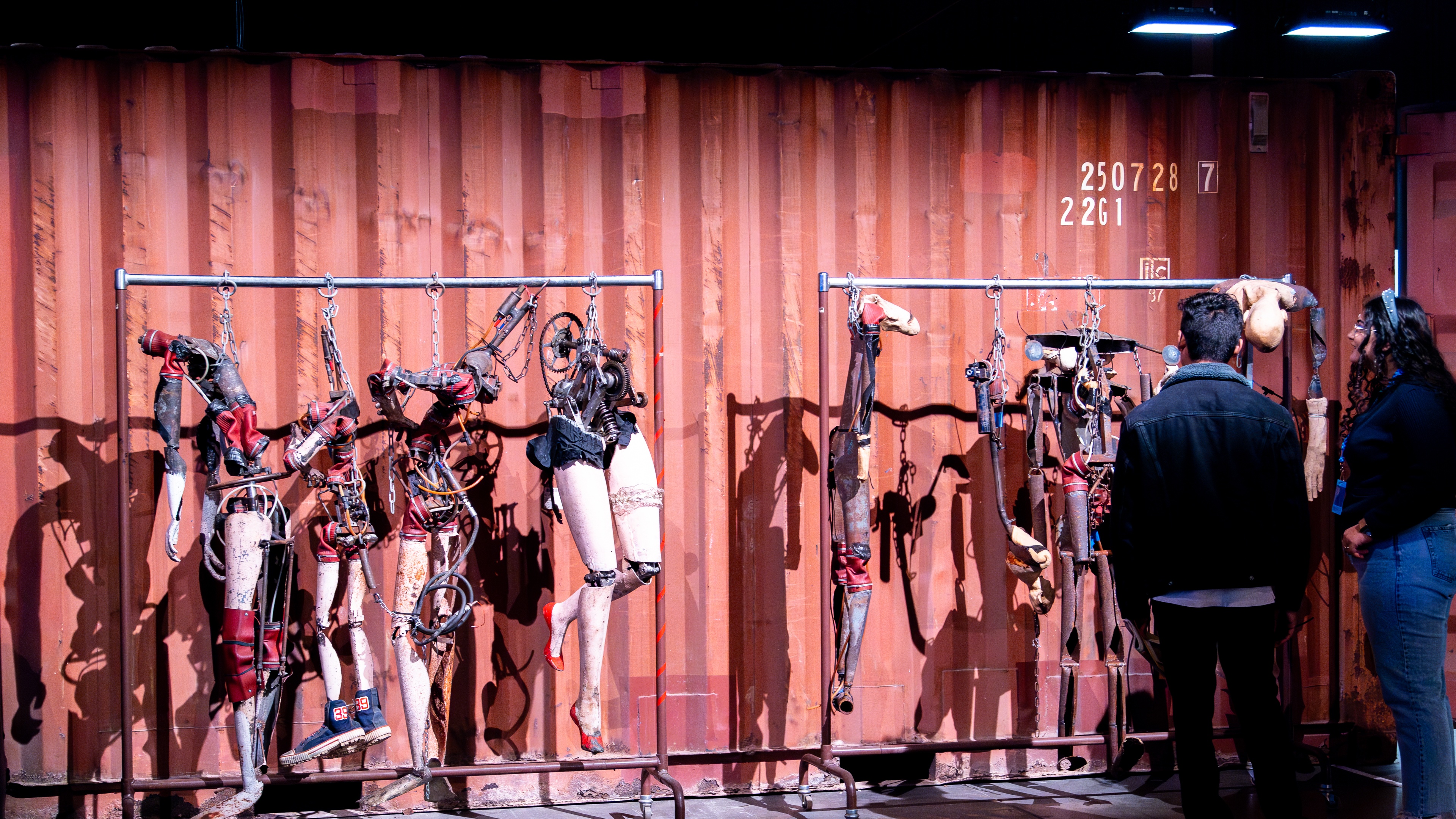 Luna luna Forgotten Fantasy male and female standing in front of rack containing vintage body part sculptures