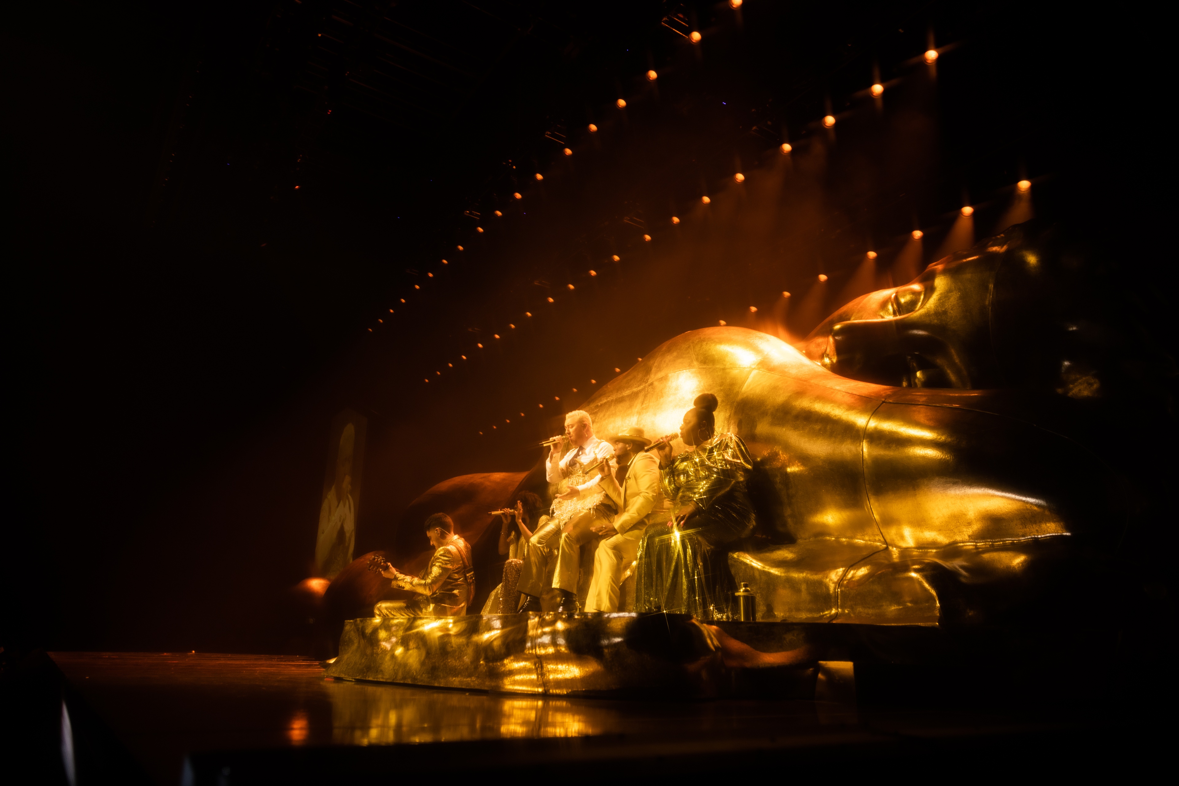 Sam Smith on stage in front of gold Gloria sculpture
