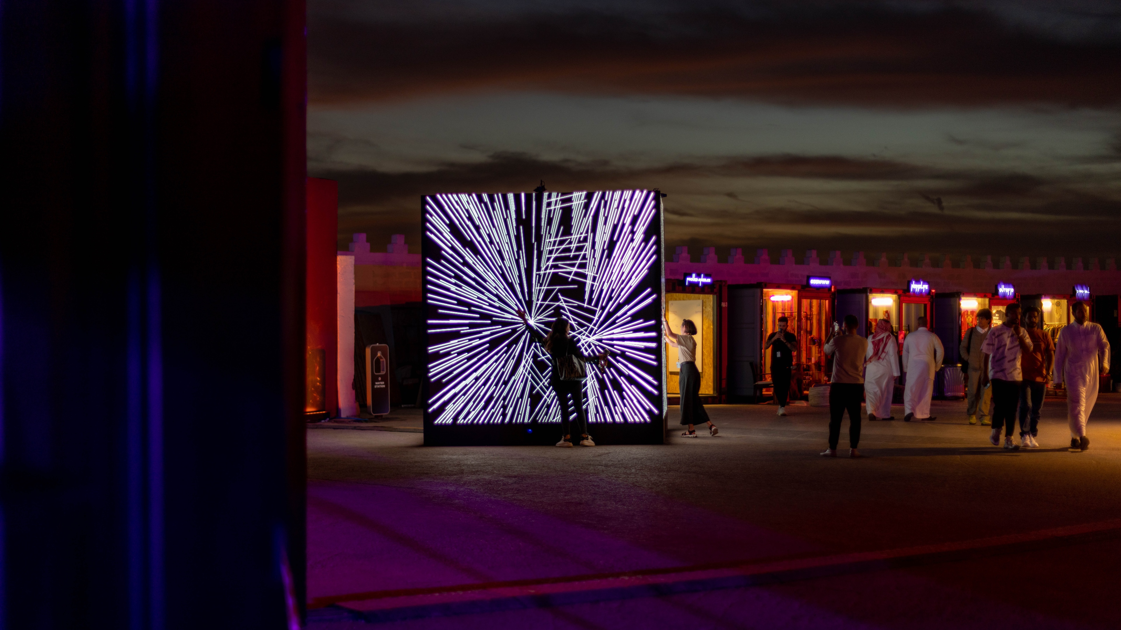 Person touching a large interactive screen, the content on the screen is thin white lines angled towards the person.