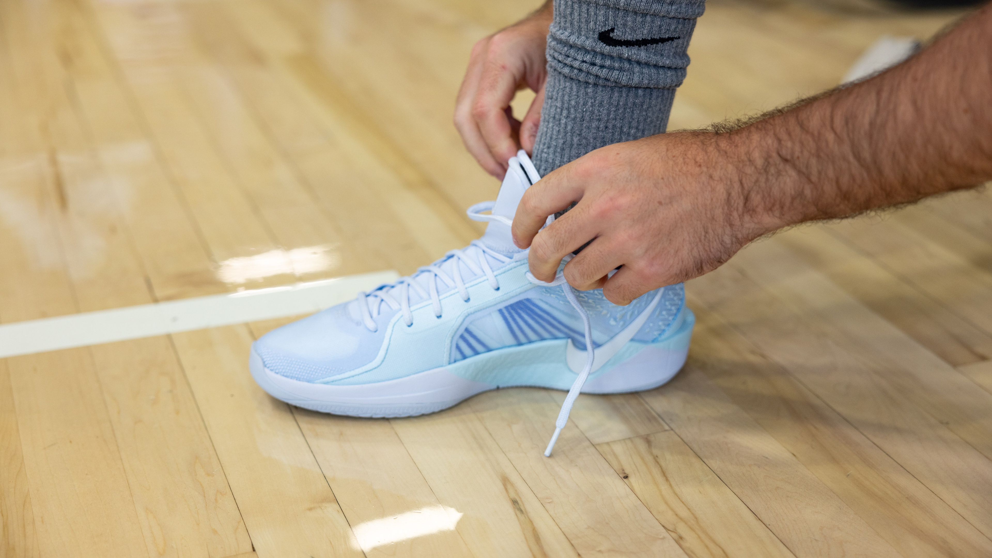 Person lacing up white Nike shoes