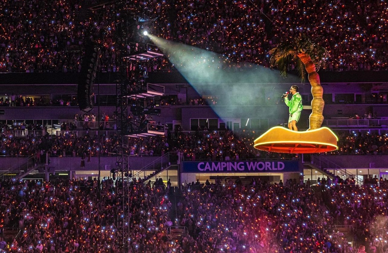 Bad Bunny flying above crowd on palm tree while performing