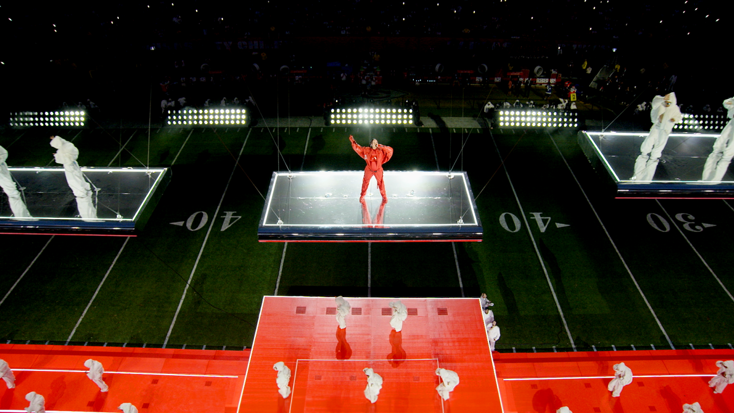 top down view of Rihanna performing on a floating stage with other dancers in background